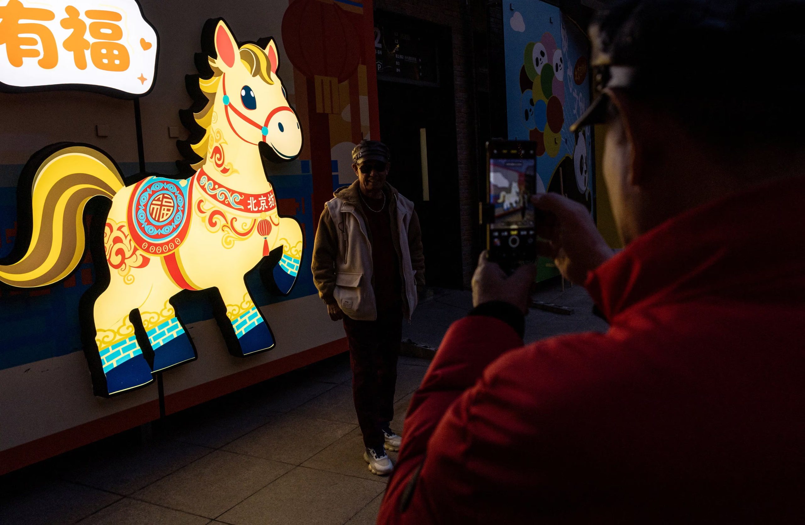 La gente se toma fotos junto a una instalación que representa un caballo antes del Año Nuevo Lunar, en una calle turística de Pekín, China, el 13 de febrero de 2026. REUTERS/Maxim Shemetov