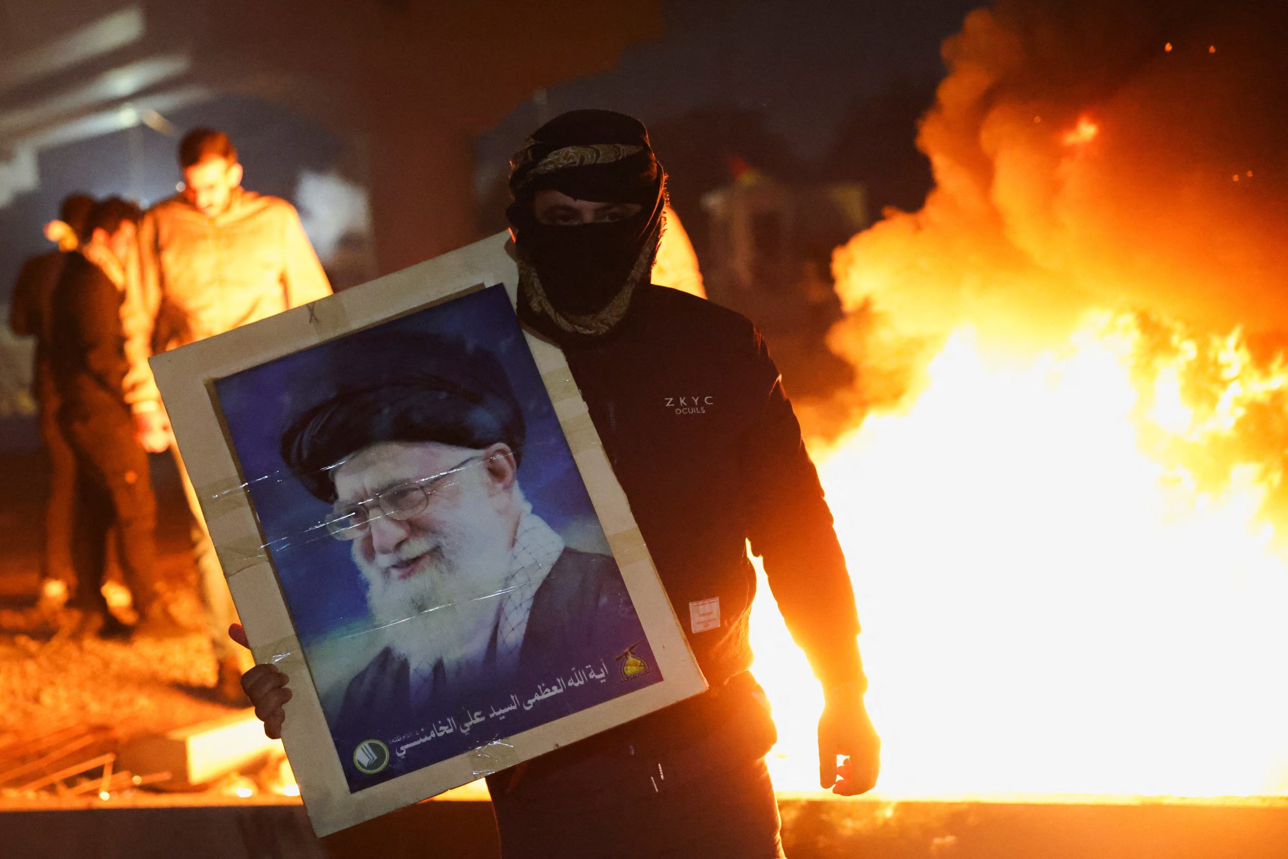 Partidarios de milicias chiíes iraquíes muestran el retrato de Ali Khamenei durante un intento de marcha hacia la embajada estadounidense en Bagdad, frenado por la policía tras los bombardeos a Irán y la muerte del líder supremo (REUTERS/Ahmed Saad)