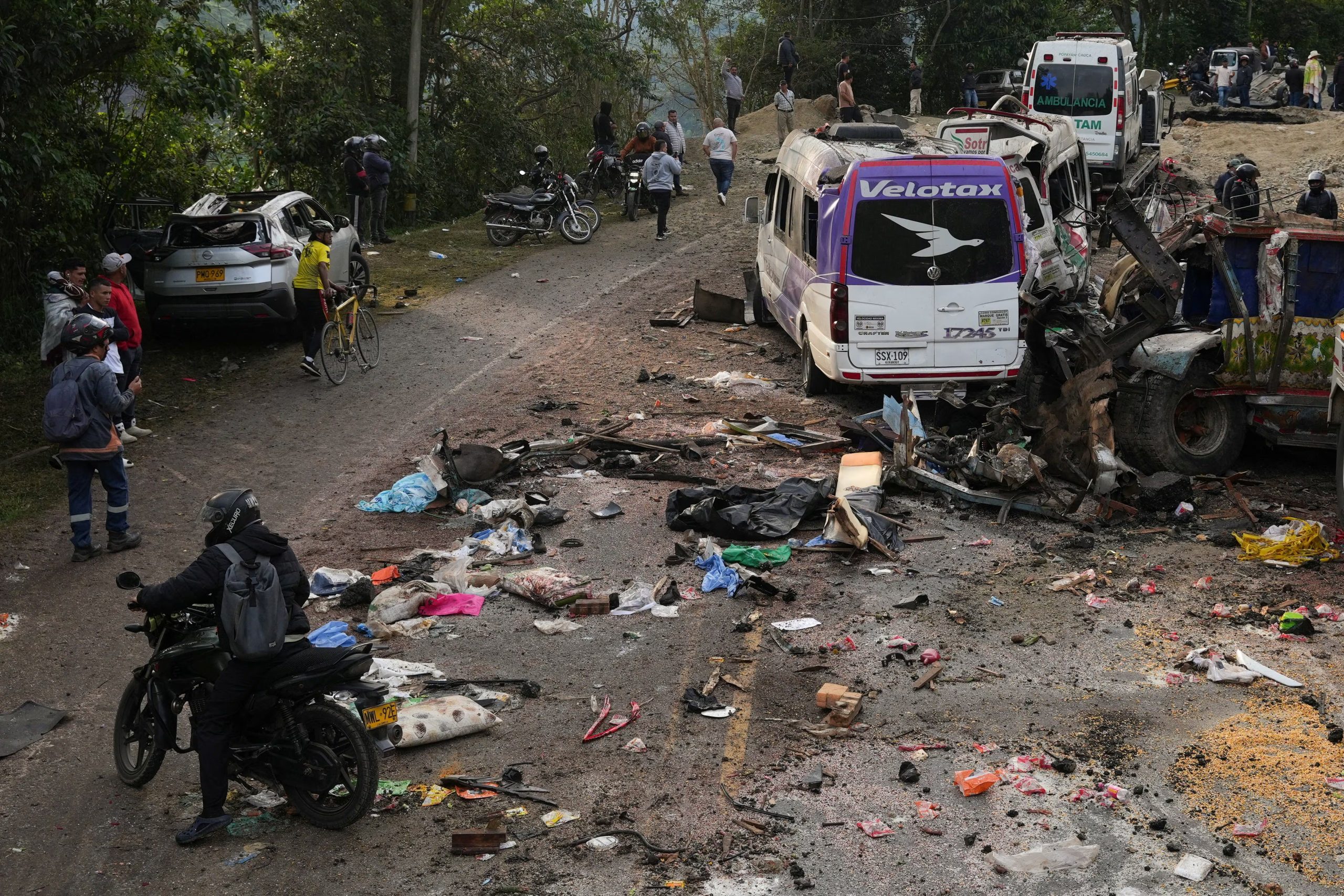 Varias personas permanecen junto a vehículos dañados tras un ataque con explosivos en el que murieron más de una docena de personas en la carretera Panamericana, en la zona de El Tunel, en Cajibio, Colombia, 26 de abril, 2026. REUTERS/Jair Coll