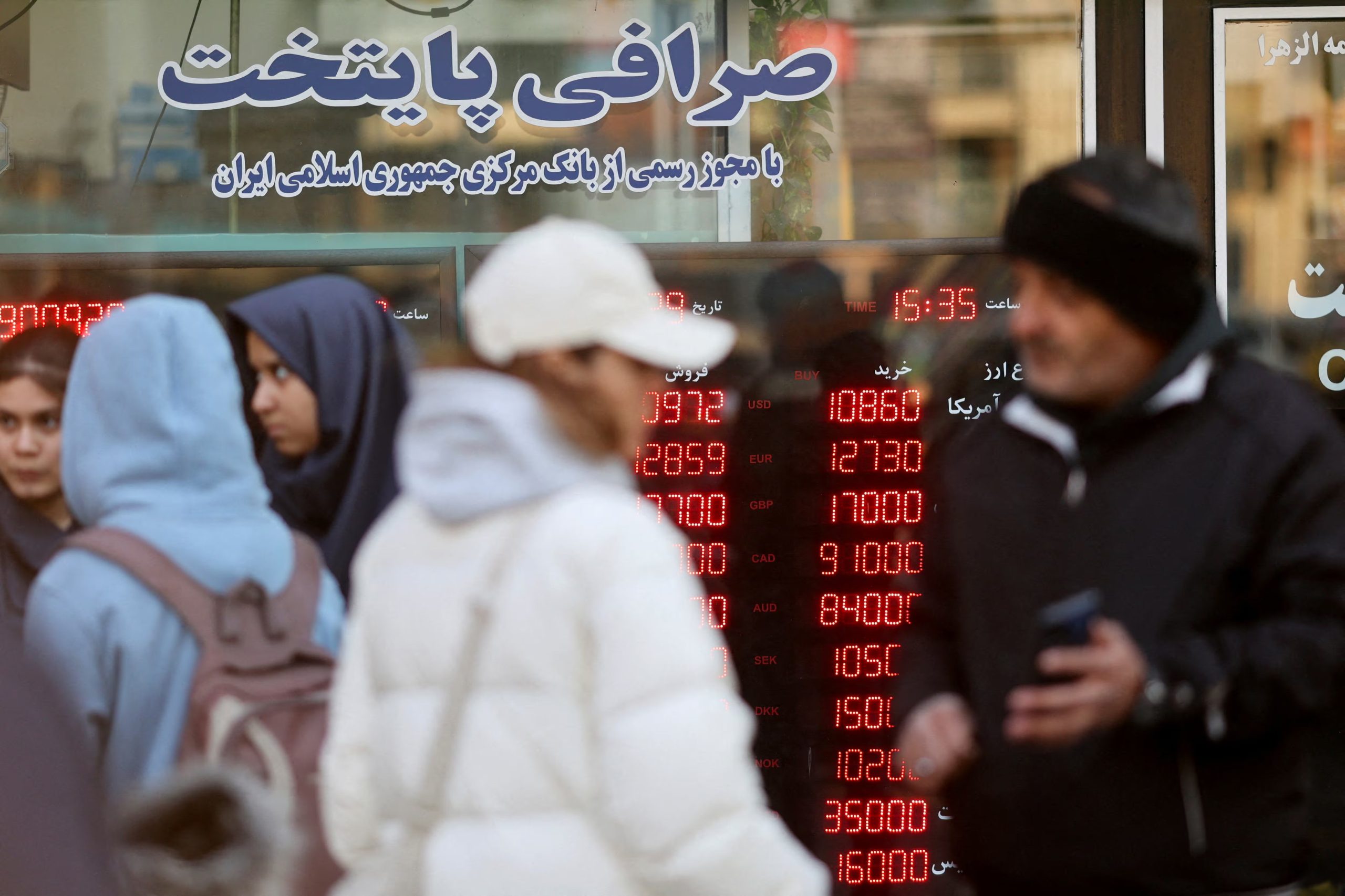 Varias personas pasan junto a un cartel informativo en una casa de cambio mientras el valor del rial iraní cae, en Teherán, Irán. Majid Asgaripour/WANA (Agencia de Noticias de Asia Occidental) vía REUTERS