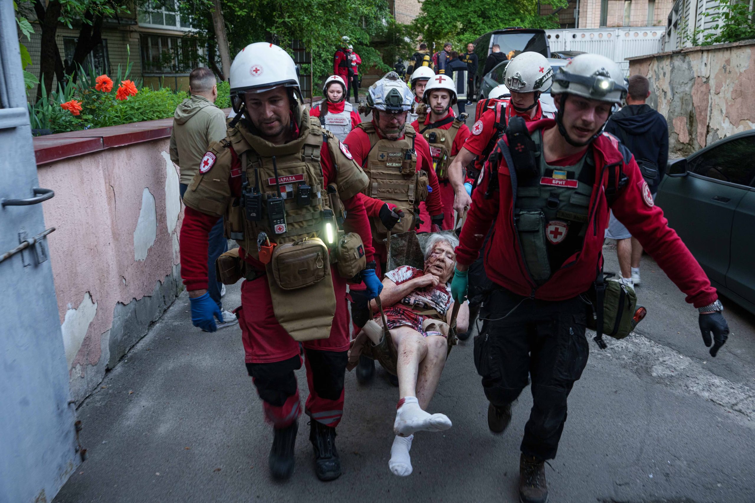 Voluntarios de la Cruz Roja trasladan a una mujer herida a una ambulancia tras un ataque ruso en un barrio residencial de Kiev.