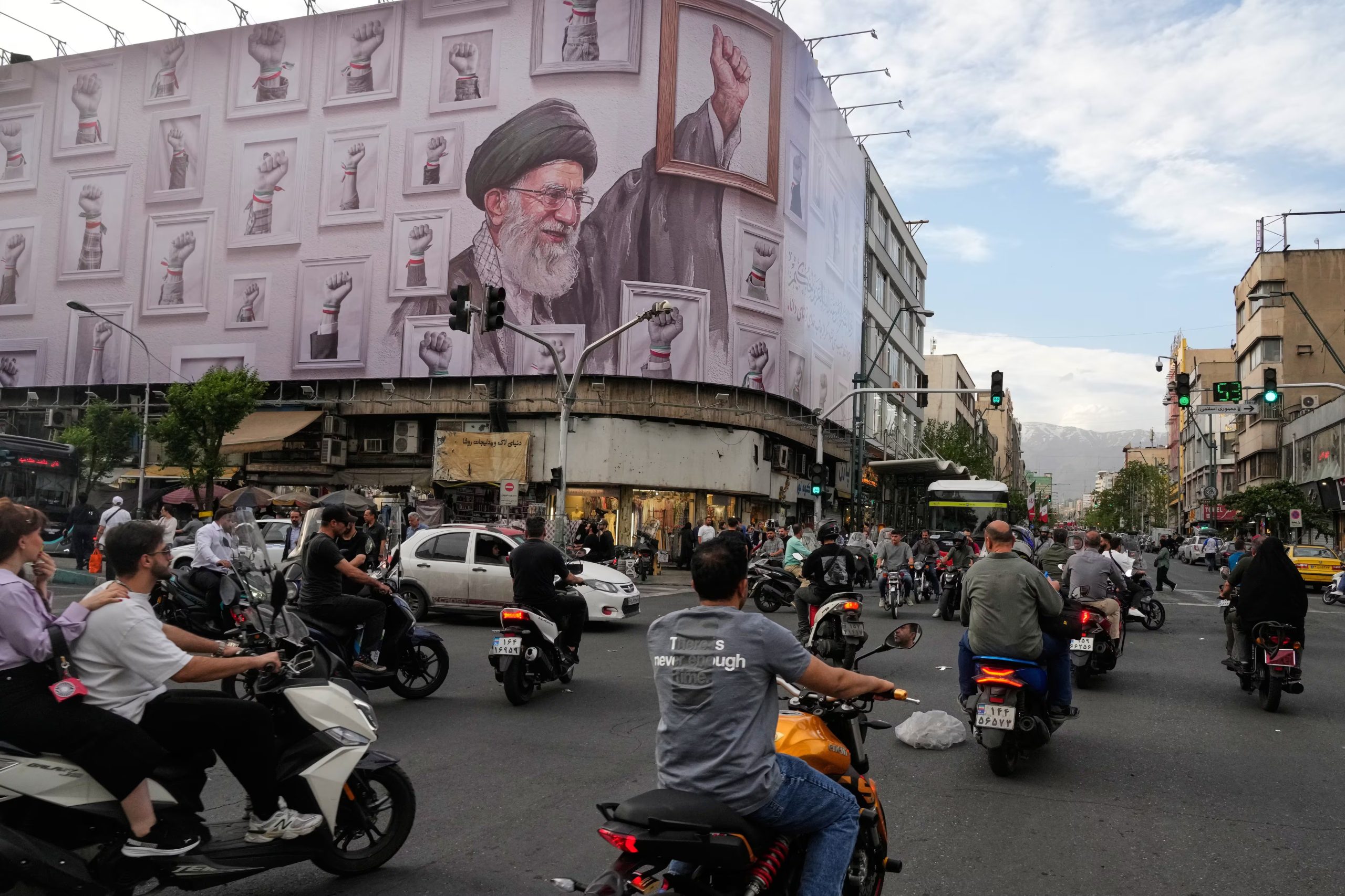 Motociclistas pasan ante un cartel con la imagen del ayatolá Alí Khamenei, líder supremo de Irán muerto en los ataques estadounidenses e israelíes del 28 de febrero, en el centro de Teherán el 6 de mayo de 2026. (Vahid Salemi/AP)