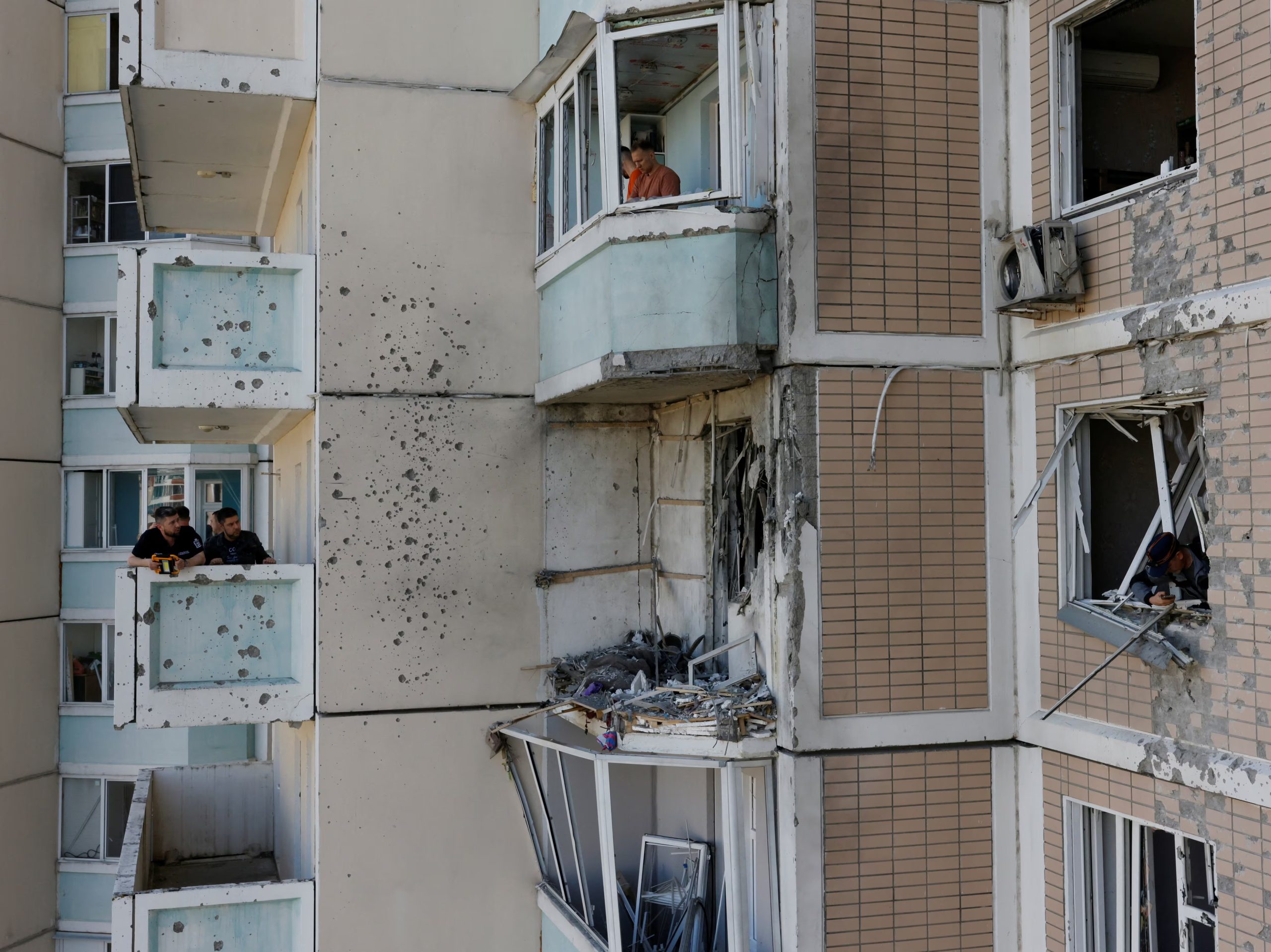 Los vecinos retiran los escombros de las ventanas rotas de un edificio de apartamentos dañado tras un ataque con drones ucranianos en el marco del conflicto entre Rusia y Ucrania en Krasnogorsk, en la región de Moscú (REUTERS/Stringer)