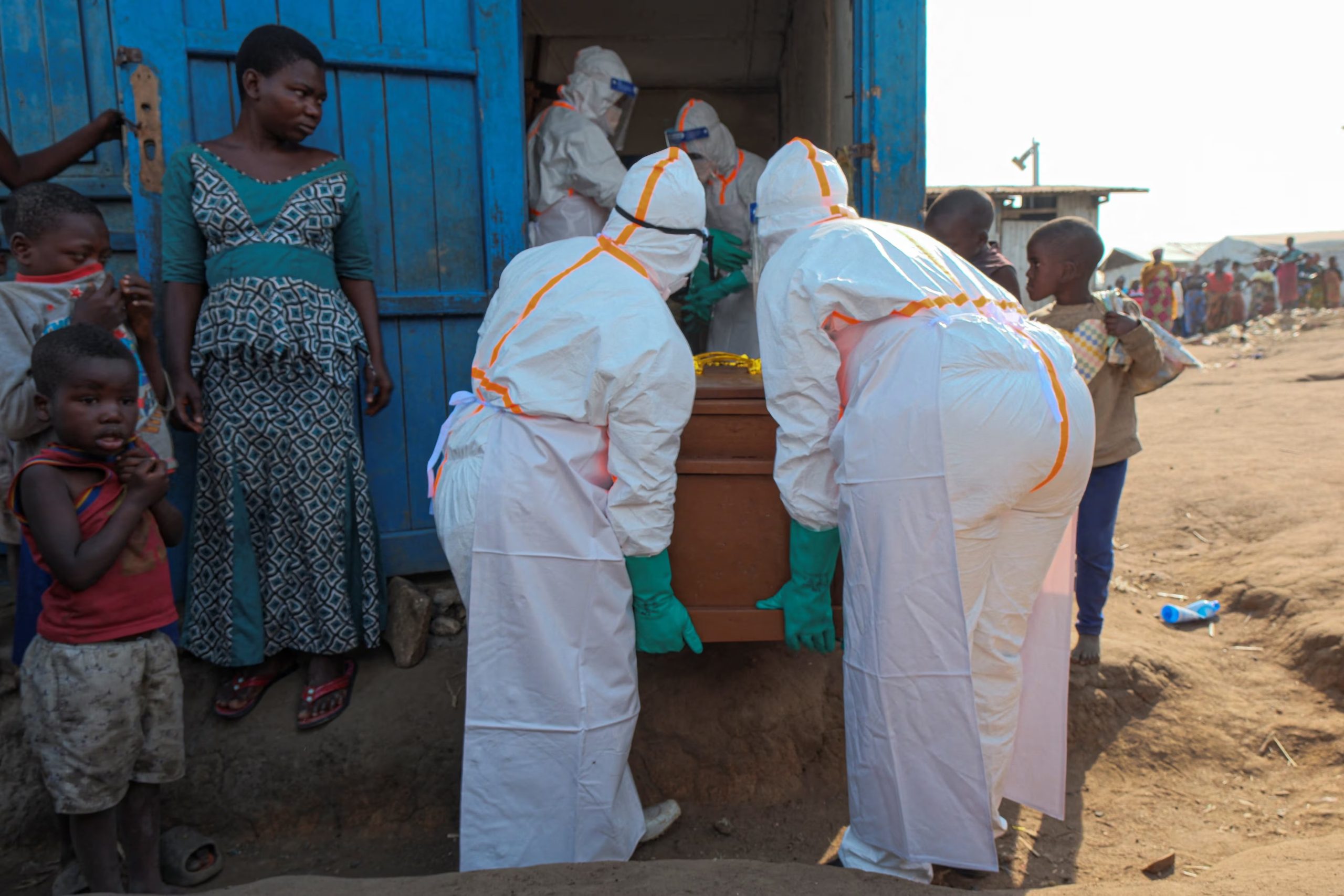 Trabajadores sanitarios con equipos de protección individual (EPI) transportan el ataúd de una víctima de ébola desde una estructura utilizada como morgue, mientras se preparan para el entierro en el cementerio de Nyamurongo. (REUTERS/Gradel Muyisa Mumbere)