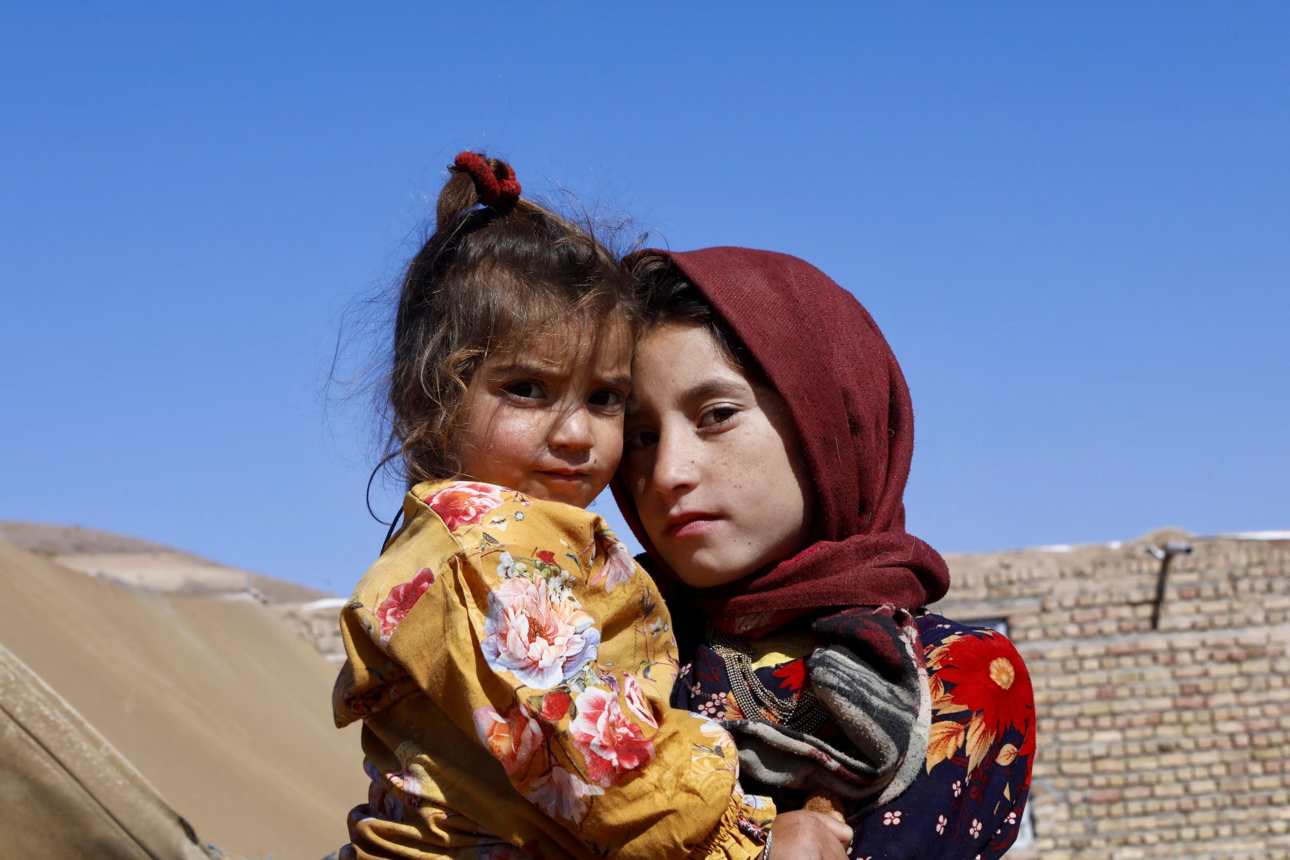 Una niña afgana carga a su hermana en el pueblo de Markhor-e-Sufla, en la provincia de Herat (REUTERS/Sayed Hassib/archivo)