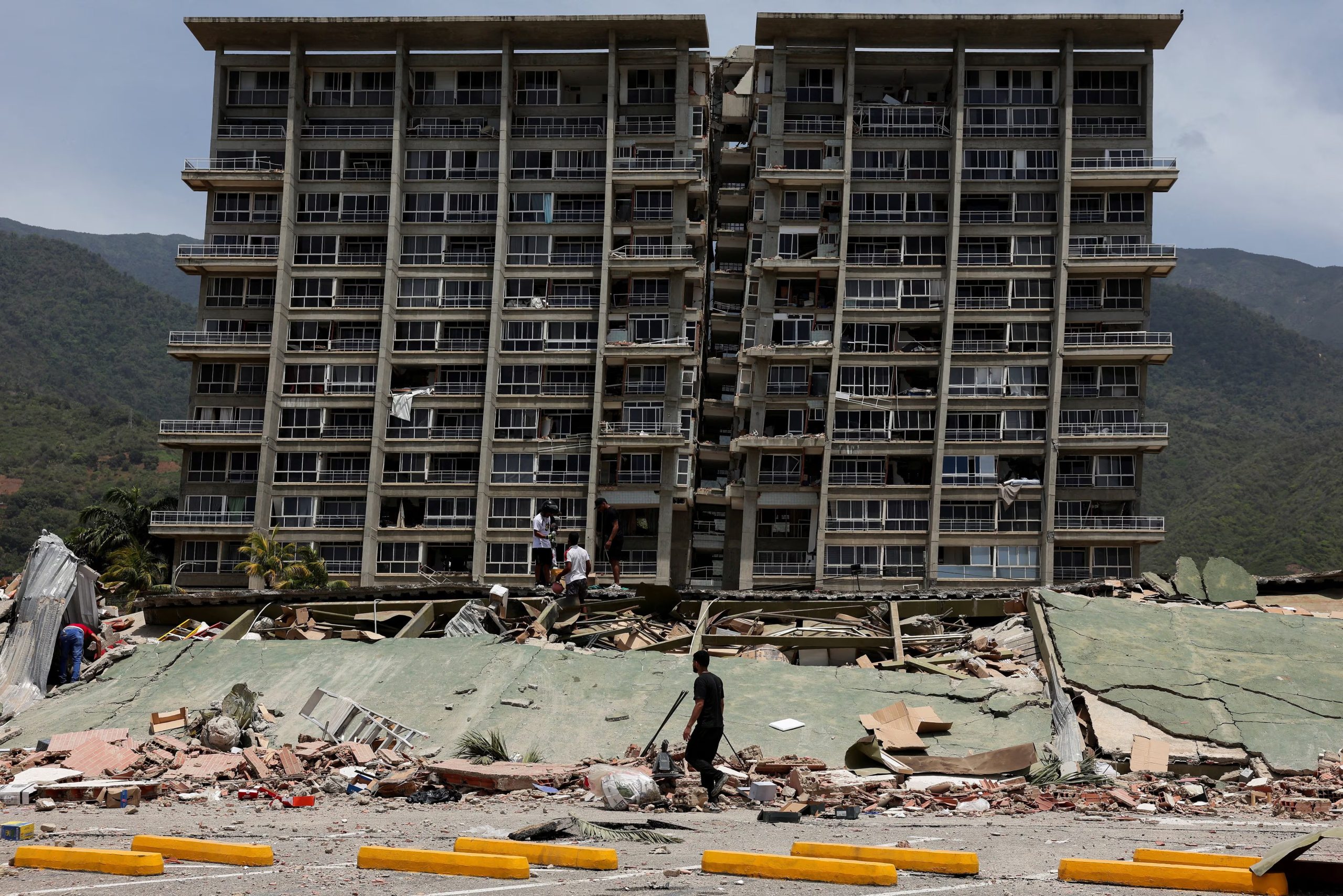 Varias personas inspeccionan los escombros de un edificio derrumbado tras los terremotos que sacudieron el país, en La Guaira, Venezuela - crédito Reuters