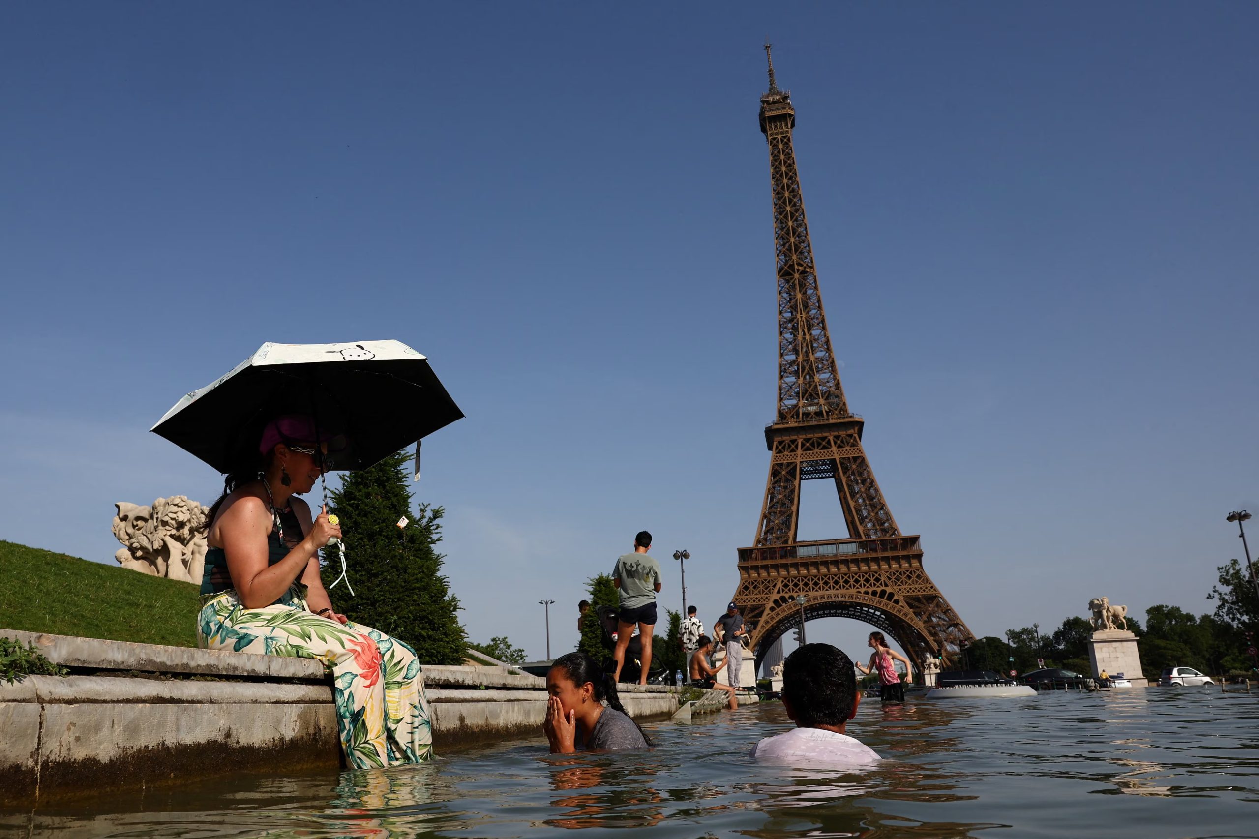 La gente se refresca en la fuente del Trocadero, frente a la Torre Eiffel, mientras las temperaturas suben en París durante una ola de calor que afecta a gran parte de Francia, 23 de junio de 2026. (Abdul Saboor/REUTERS)