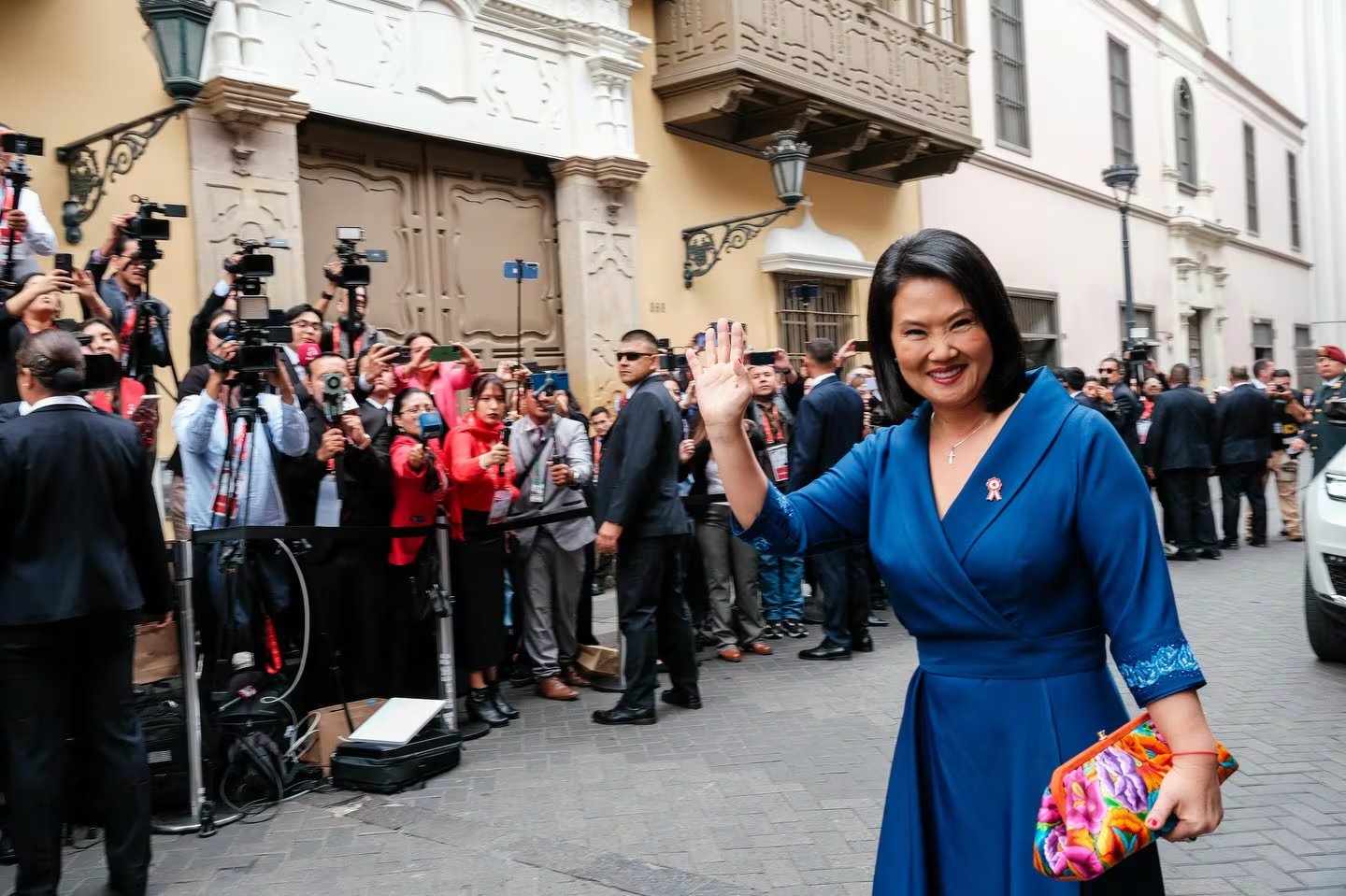 Keiko Fujimori, vestida de azul y con un bolso colorido, saluda a la prensa y al público al inicio de sus actividades protocolares en Perú. (Oficina de la presidenta electa)