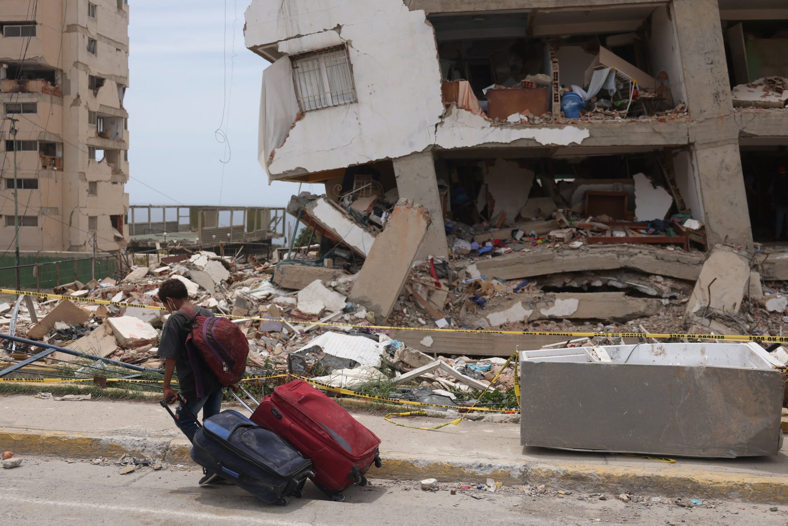 Un edificio de la Gran Misión Vivienda Venezuela dañado por los terremotos del 24 de junio en Catia La Mar. Frente a él, un niño carga equipaje mientras continúa la emergencia en La Guaira (REUTERS/Leonardo Fernandez Viloria)
