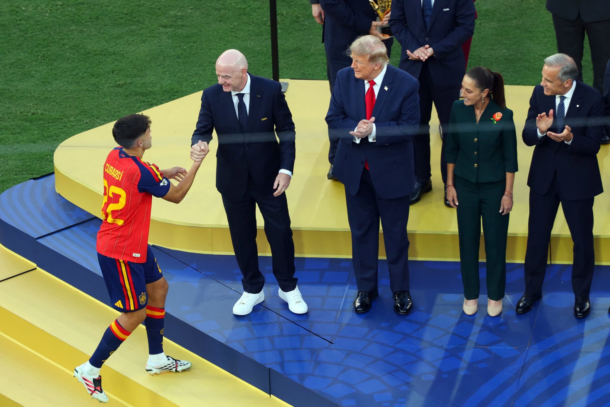 Pau Cubarsi, de España, estrecha la mano del presidente de la FIFA, Gianni Infantino, en el podio tras ganar el premio al Mejor Jugador Joven después de ganar la Copa del Mundo, mientras el presidente de Estados Unidos, Donald Trump, observa