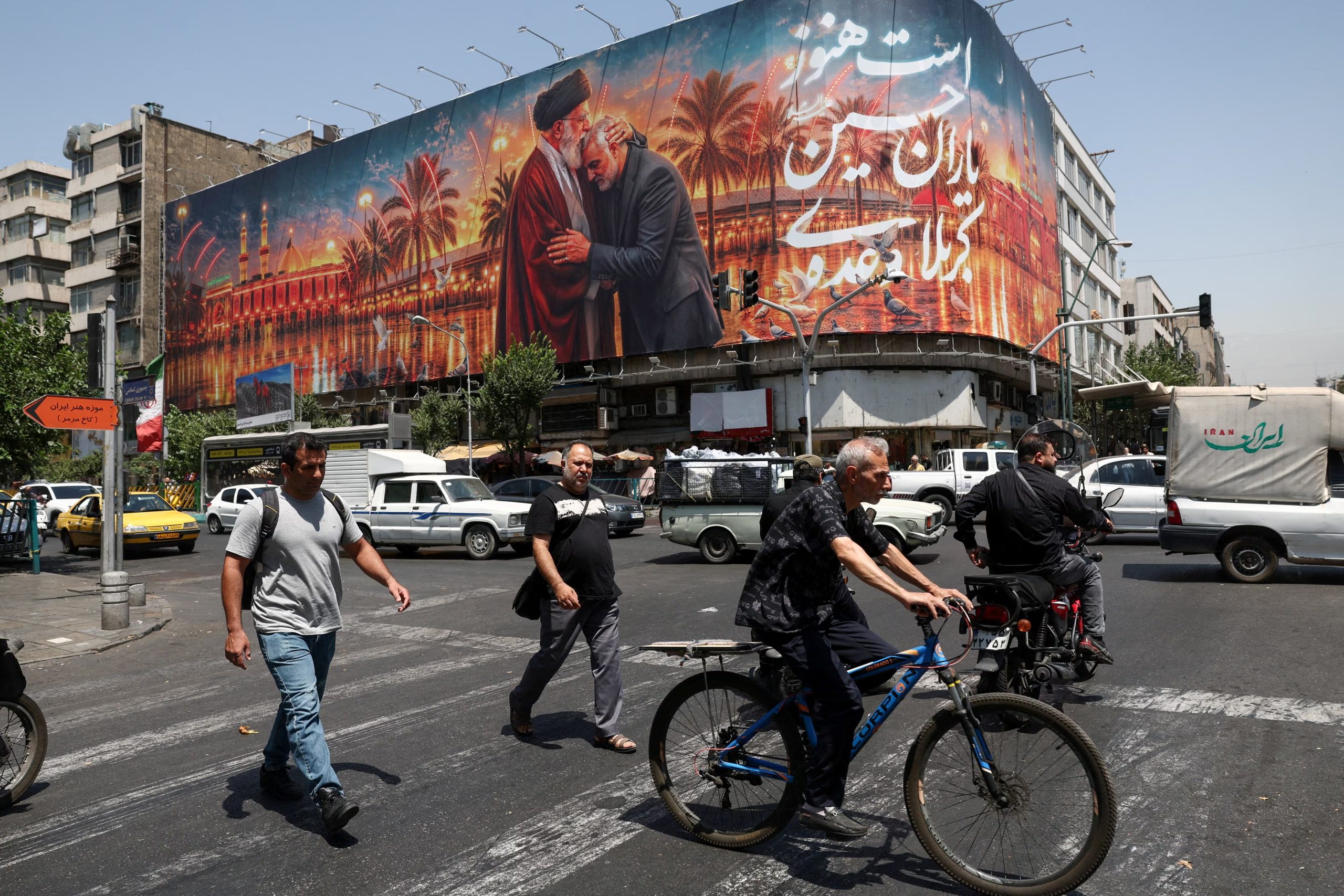 Personas pasan junto a una valla publicitaria con una imagen que muestra al difunto líder supremo de Irán, el ayatollah Ali Khamenei, abrazando al también fallecido comandante militar iraní, el general Qassem Soleimani, en Teherán, Irán (Majid Asgaripour/WANA vía REUTERS/Archivo)