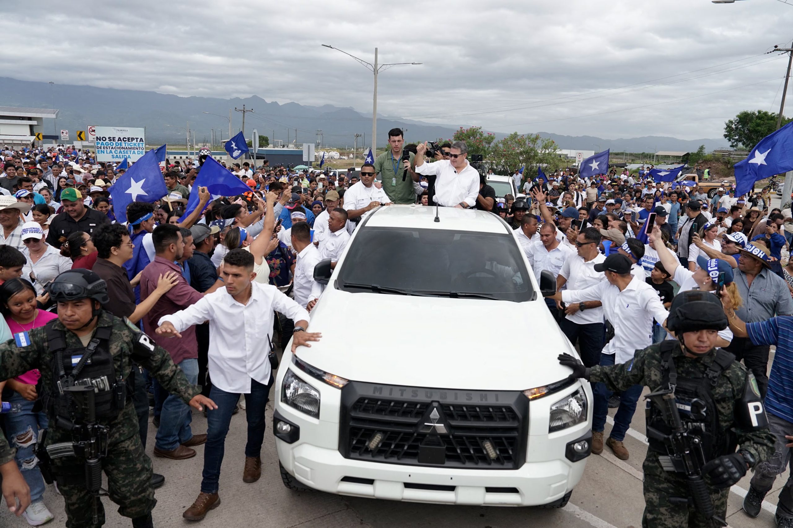 El expresidente hondureño Juan Orlando Hernández saluda a sus seguidores tras su llegada al Aeropuerto Internacional de Palmerola, luego de recibir el indulto del presidente estadounidense Donald Trump, que lo liberó de una condena de 45 años de prisión por conspirar para importar cocaína a Estados Unidos, cerca de Comayagua, Honduras, el 26 de julio de 2026. REUTERS/Leonel Estrada