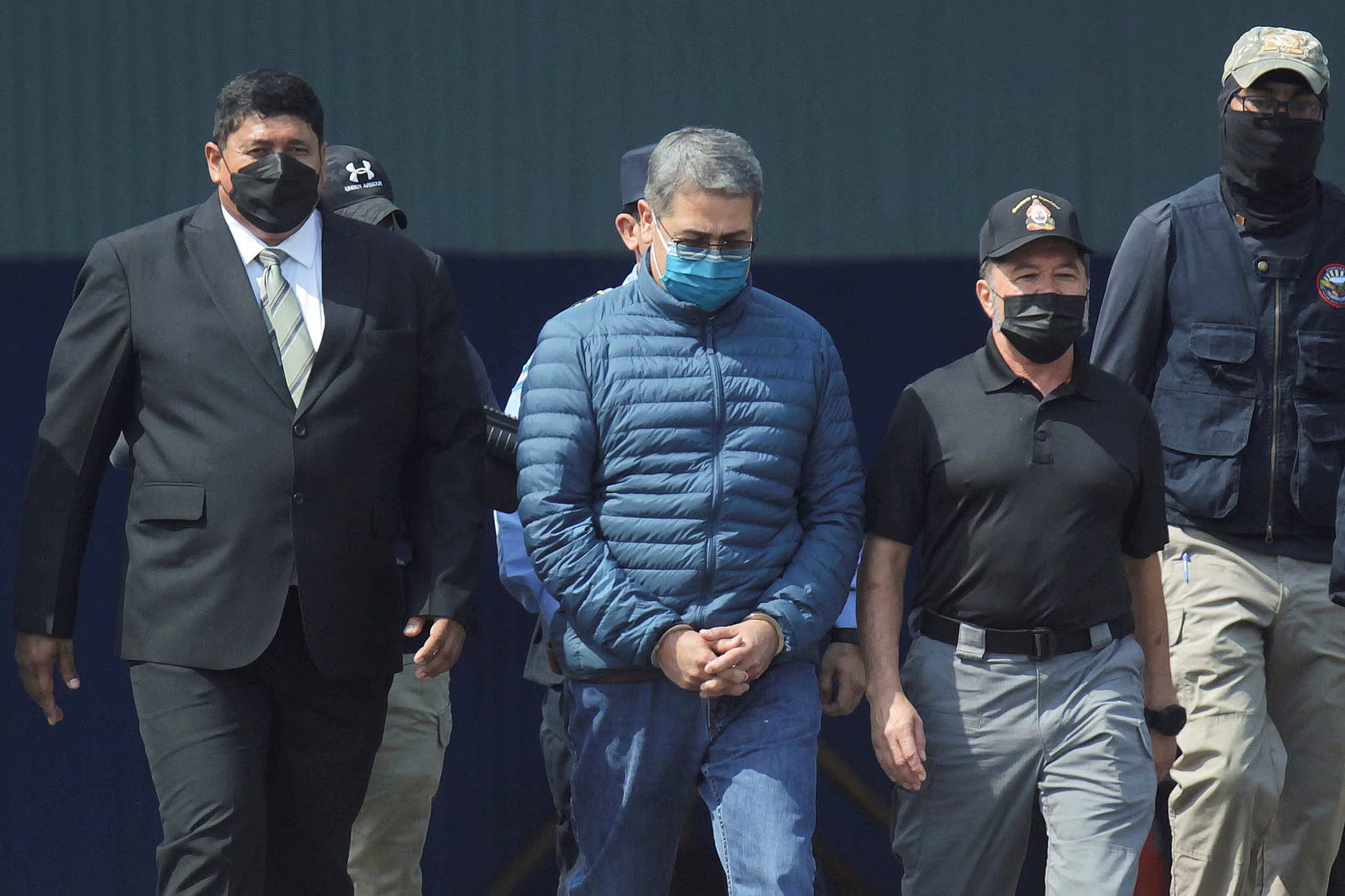 FOTO DE ARCHIVO: El expresidente de Honduras, Juan Orlando Hernández, es escoltado por las autoridades mientras camina hacia un avión de la Administración para el Control de Drogas de Estados Unidos (DEA) para su extradición a Estados Unidos, donde enfrentará un juicio por cargos de narcotráfico y posesión de armas, en la base aérea Hernán Acosta Mejía en Tegucigalpa, Honduras, el 21 de abril de 2022. REUTERS/Fredy Rodriguez/Foto de archivo