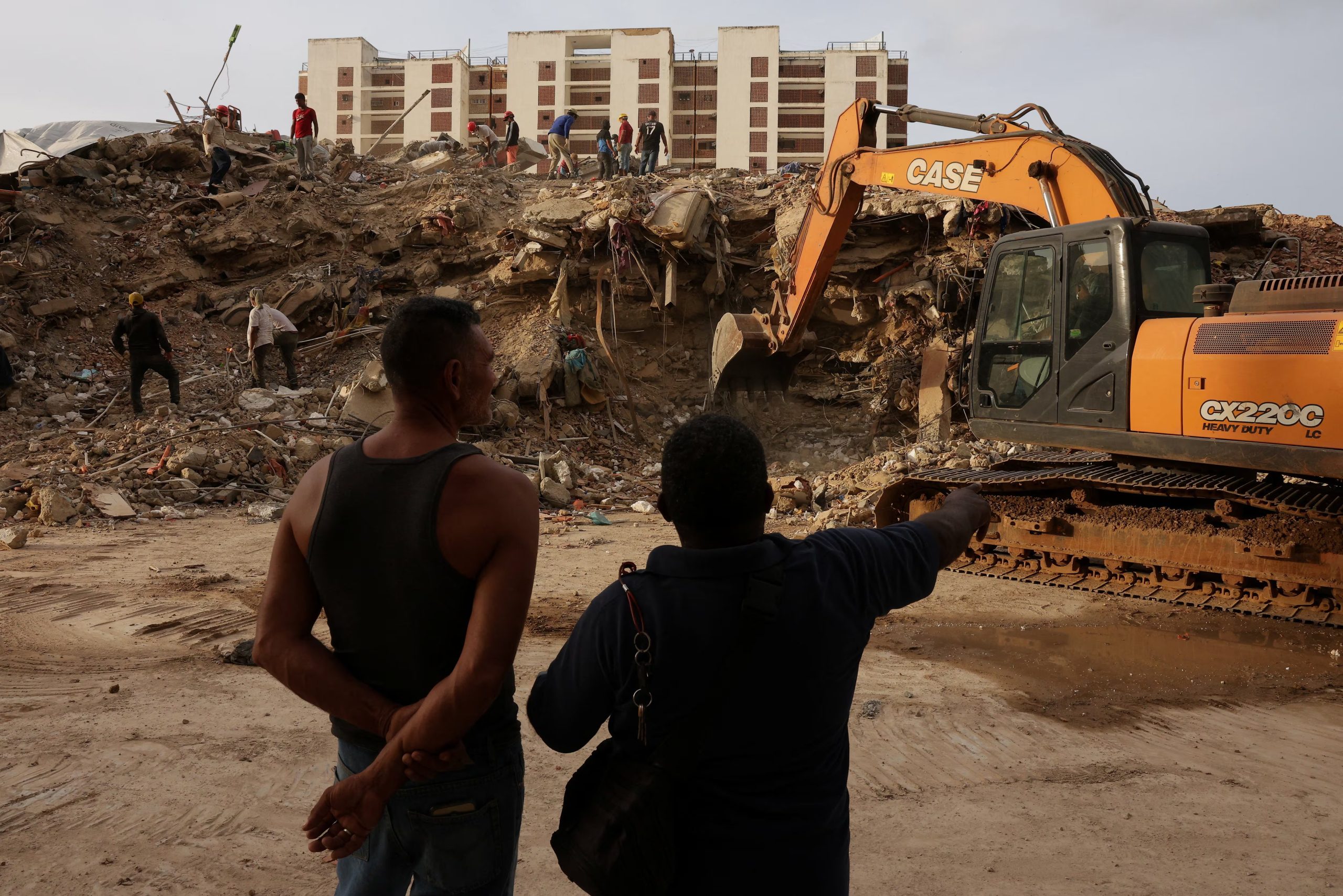 La gente observa cómo las máquinas retiran los escombros mientras buscan a sus seres queridos entre los restos, tras los terremotos del 24 de junio en Caraballeda, La Guaira (Venezuela), el 20 de julio de 2026 (REUTERS/Gaby Oraa)
