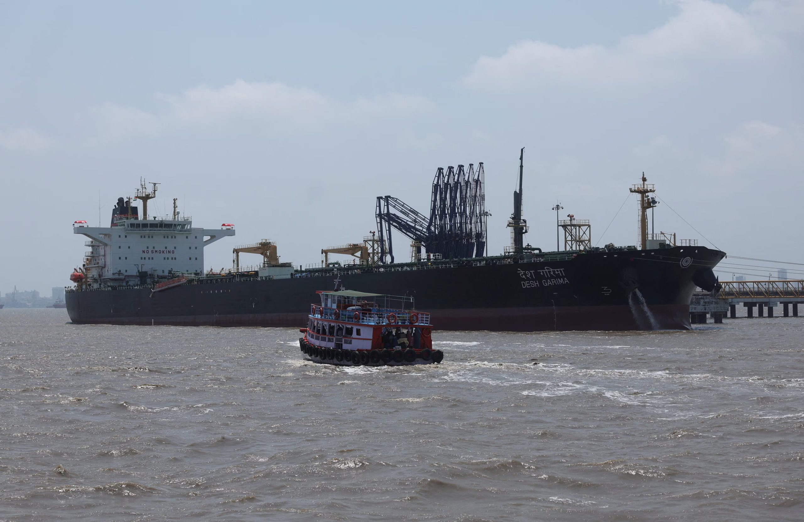 Un ferry navega junto al petrolero de bandera india Desh Garima mientras descarga crudo en una terminal de Mumbai, tras cruzar el estrecho de Ormuz en medio de las tensiones en Medio Oriente (REUTERS/Francis Mascarenhas/Archivo)