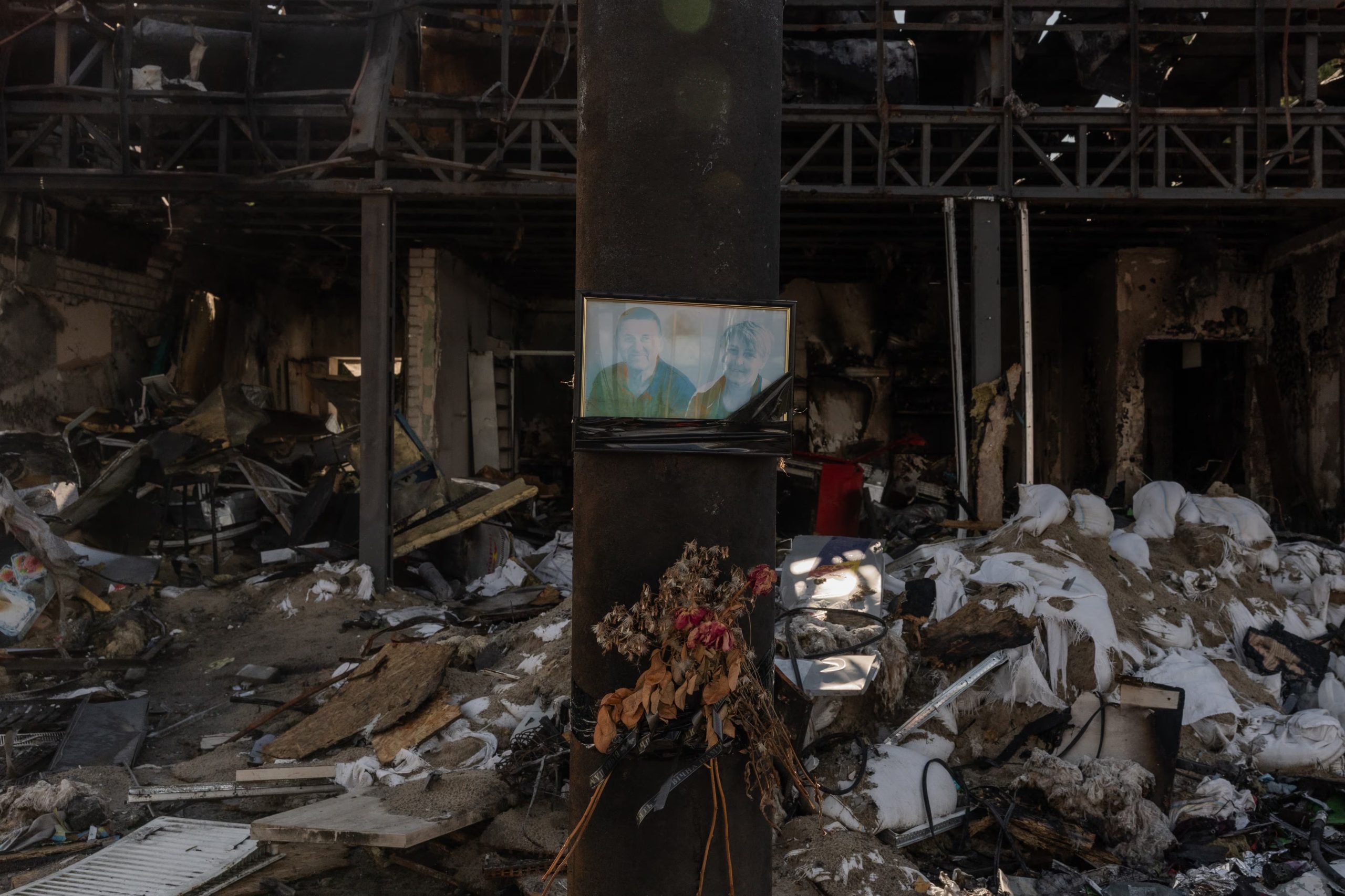 Un retrato de víctimas colocado en una gasolinera destruida por un ataque aéreo ruso en la ciudad de Izium, en la región oriental de Járkov (Roman PILIPEY / AFP)