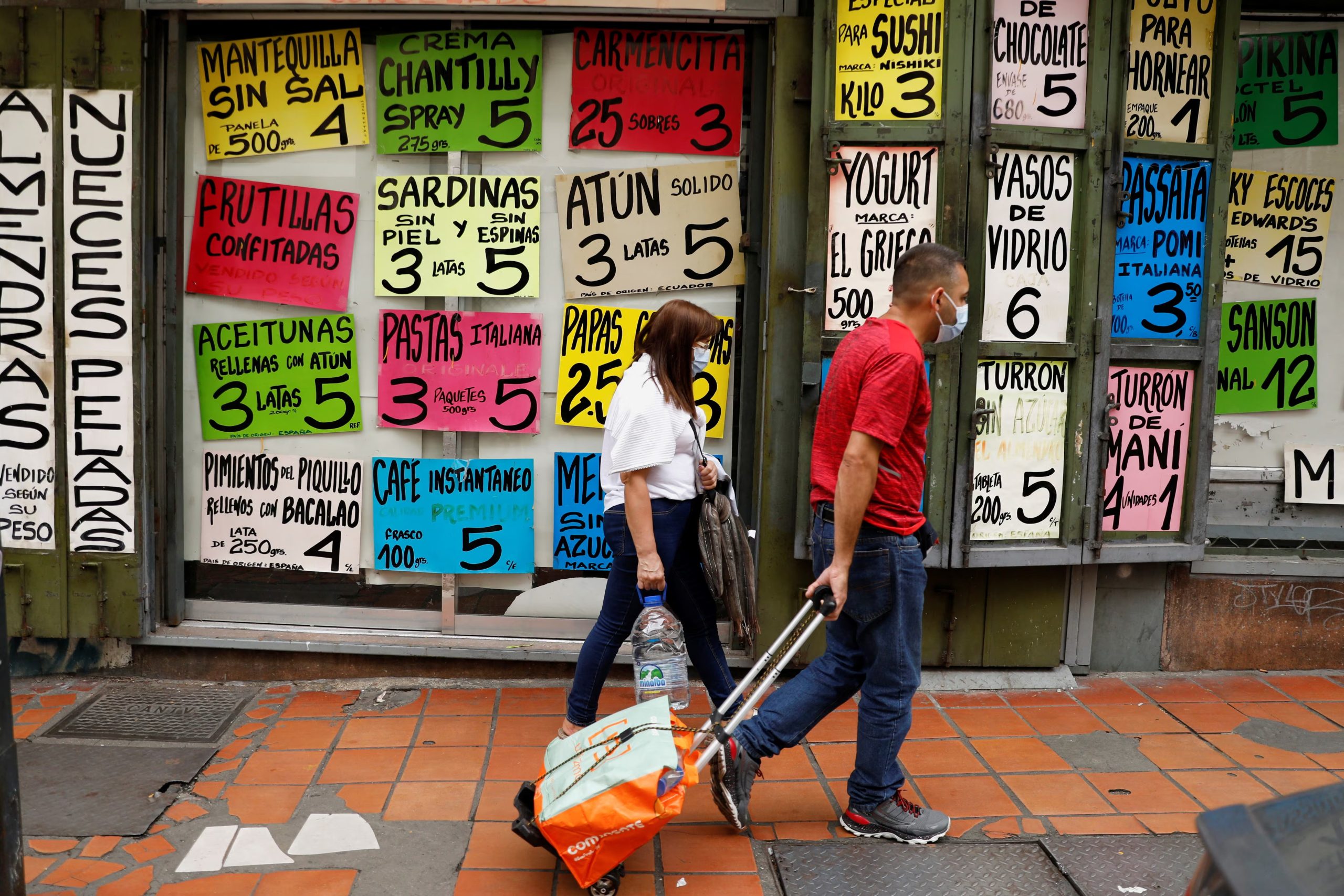 FOTO DE ARCHIVO- La gente pasa por delante de una tienda de comestibles con carteles que anuncian los precios de los alimentos, en Caracas, Venezuela 25 de agosto 2022. REUTERS/Leonardo Fernández Viloria