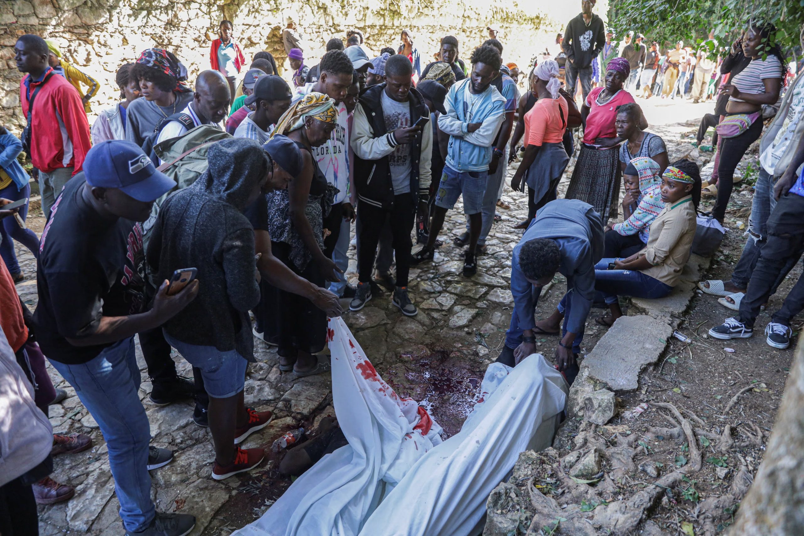 Residentes se reúnen junto a los cuerpos cubiertos de personas asesinadas durante una incursión nocturna de una banda armada, en las afueras de Puerto Príncipe, en Kenscoff, Haití, el 24 de agosto de 2026 (REUTERS/Patrice Noel)