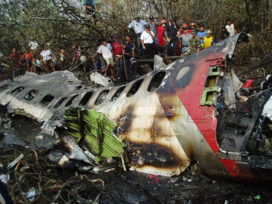 Personal de rescate y pobladores observan los restos quemados del fuselaje del vuelo 204 de TANS Perú tras su accidente en 2005. (Infobae Perú)