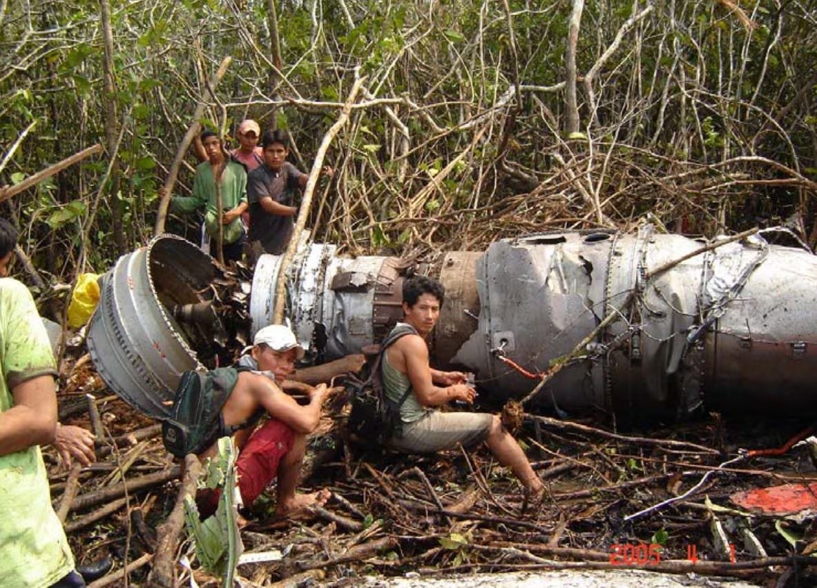 Pobladores locales observan los restos del motor del vuelo 204 de TANS Perú en una zona boscosa tras el accidente aéreo ocurrido en 2005. (Infobae Perú)