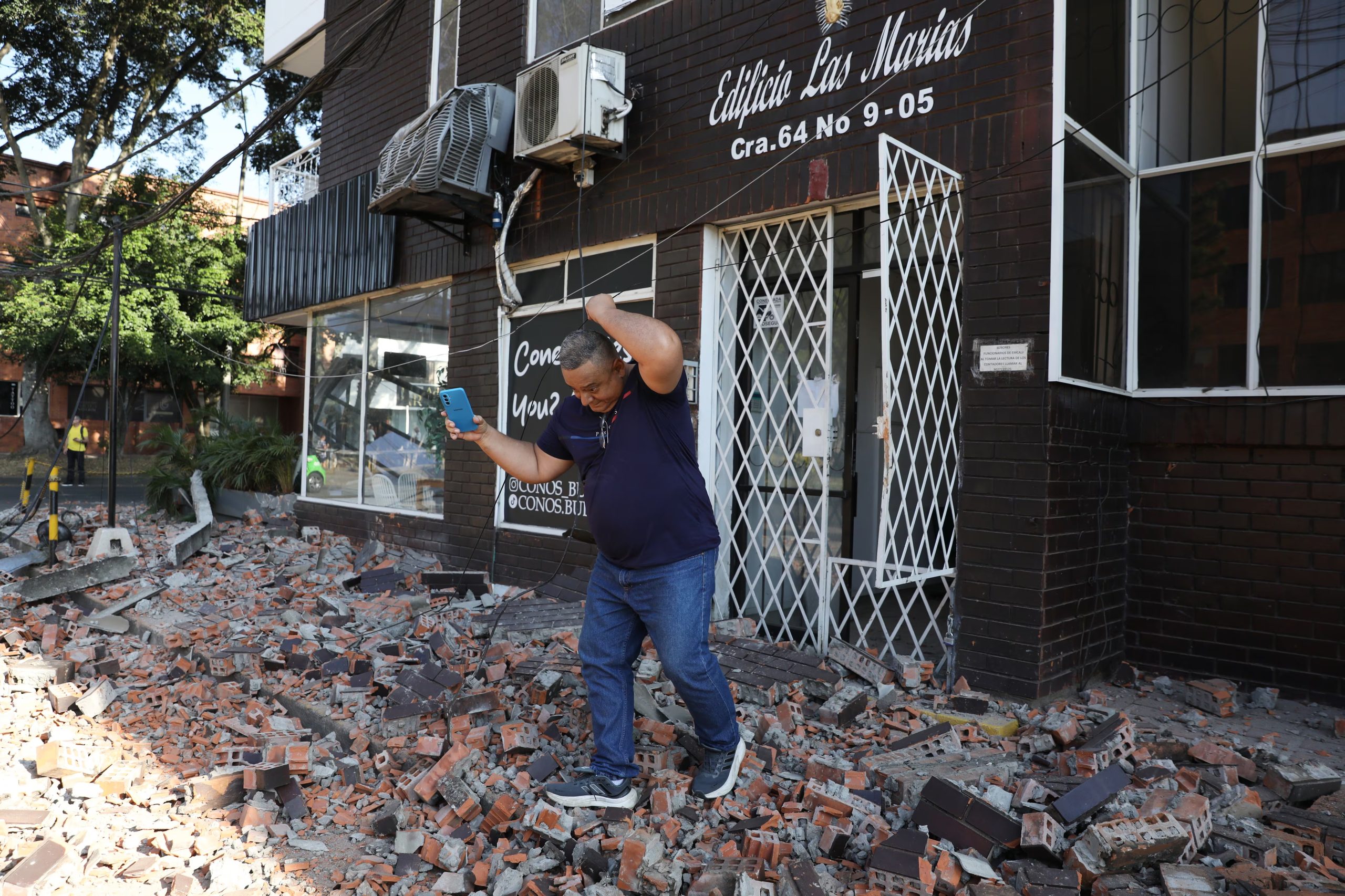 Un hombre escapa entre los escombros de un edificio en Cali