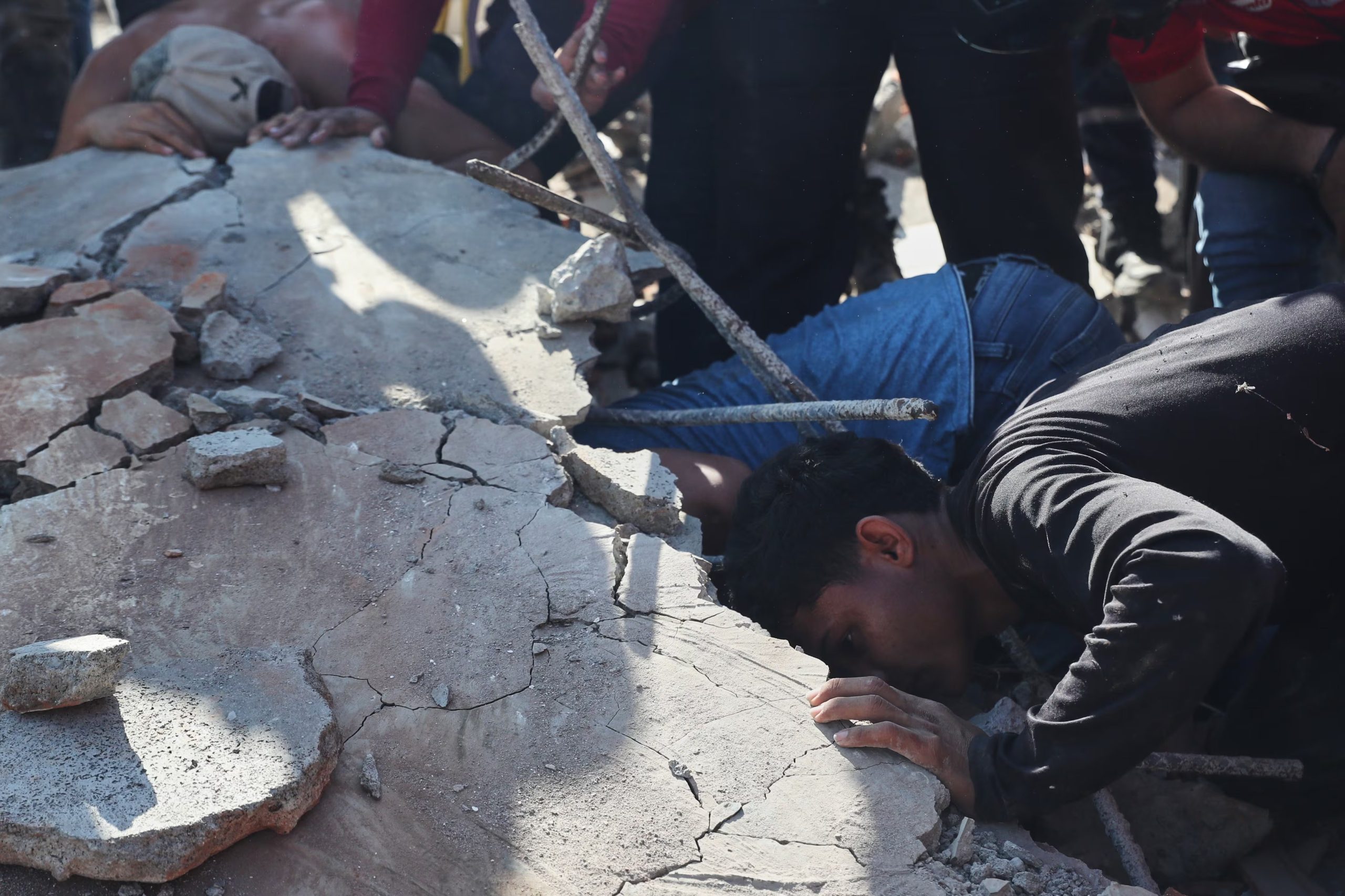 Residentes y equipos de rescate buscan entre los escombros de un edificio derrumbado