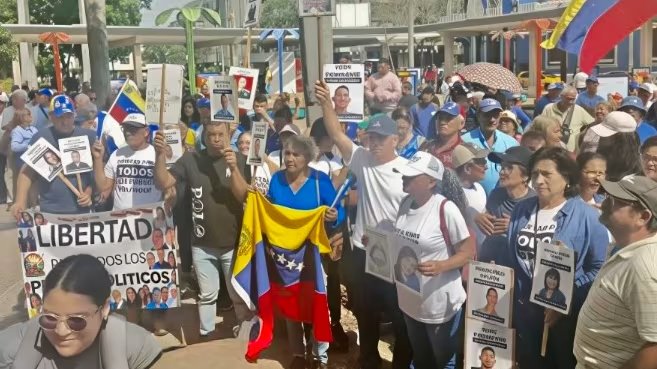 Ciudadanos venezolanos se congregan en una calle para exigir la libertad de presos políticos, ondeando banderas nacionales y portando pancartas con imágenes de detenidos (Archivo)