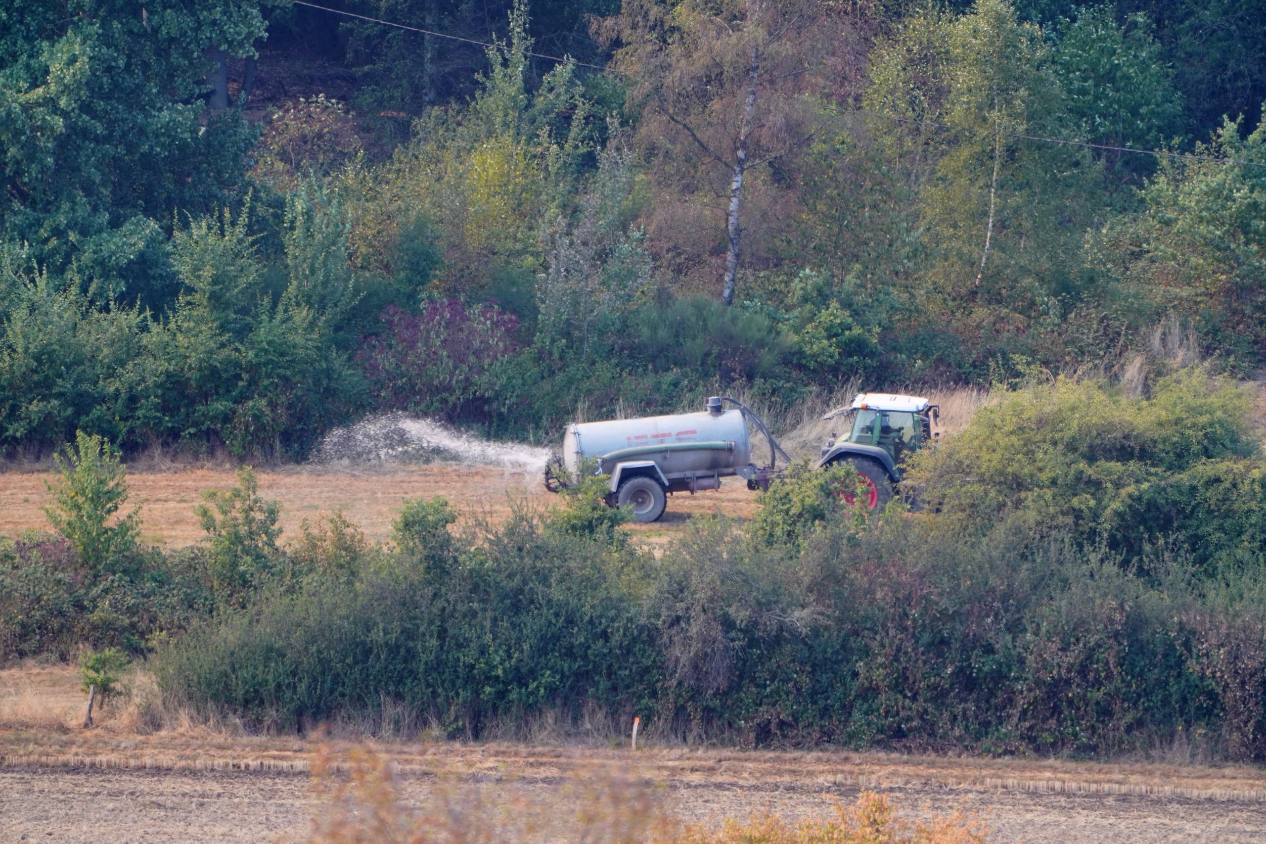 Un agricultor rocía agua cerca de una zona residencial (REUTERS/Timm Reichert)