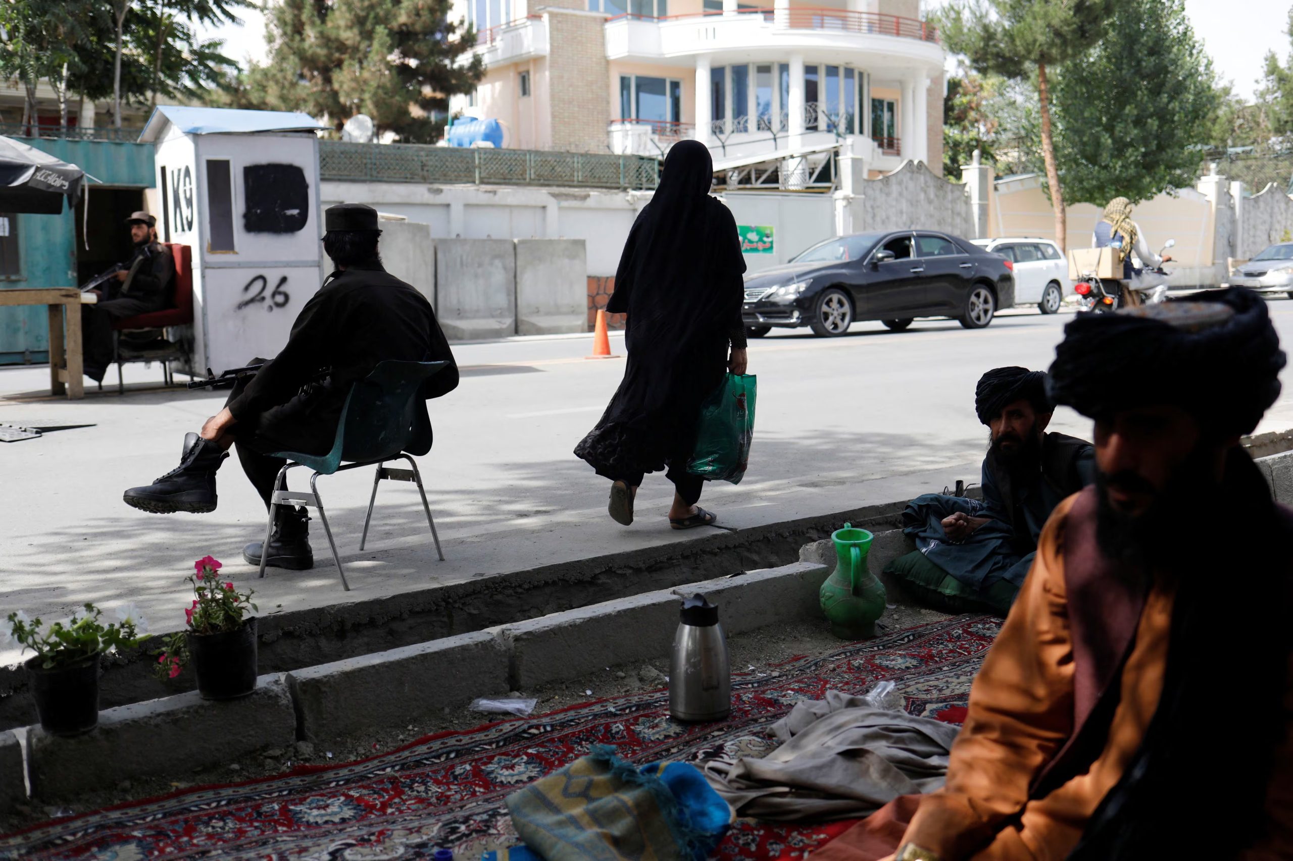 Una mujer afgana camina entre soldados talibanes en un puesto de control en Kabul, Afganistán, el 6 de julio de 2023. REUTERS/Ali Khara