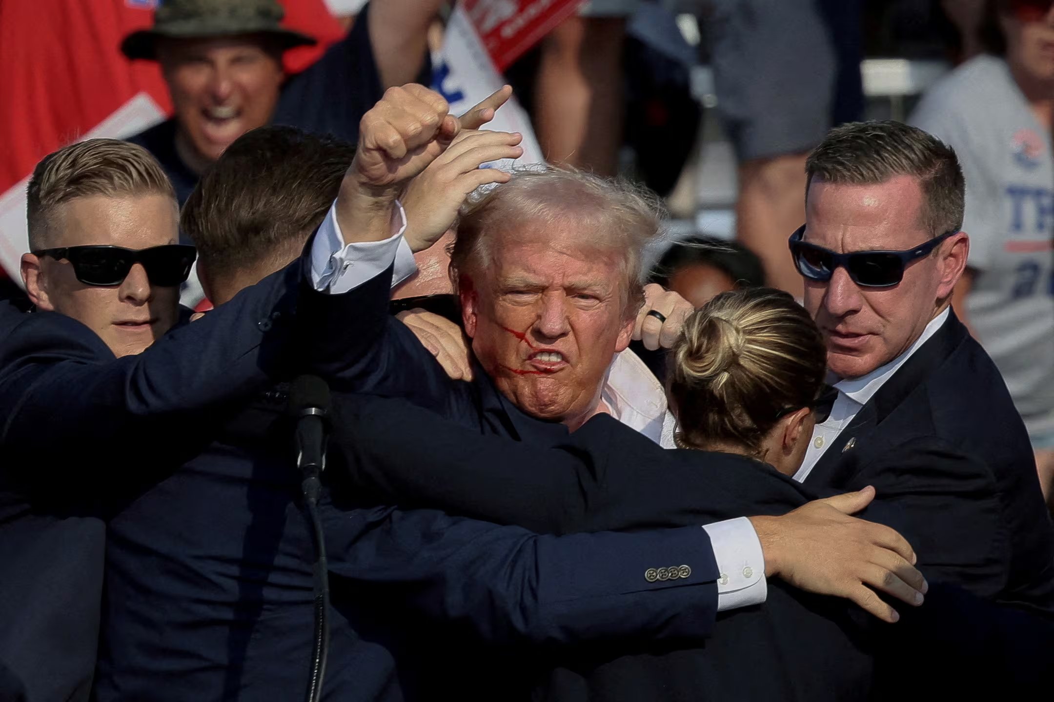 El ex candidato presidencial republicano y actual presidente de EE. UU., Donald Trump, hace un gesto con el rostro ensangrentado mientras recibe asistencia de personal del Servicio Secreto de EEUU (REUTERS/Brendan McDermid/Archivo)