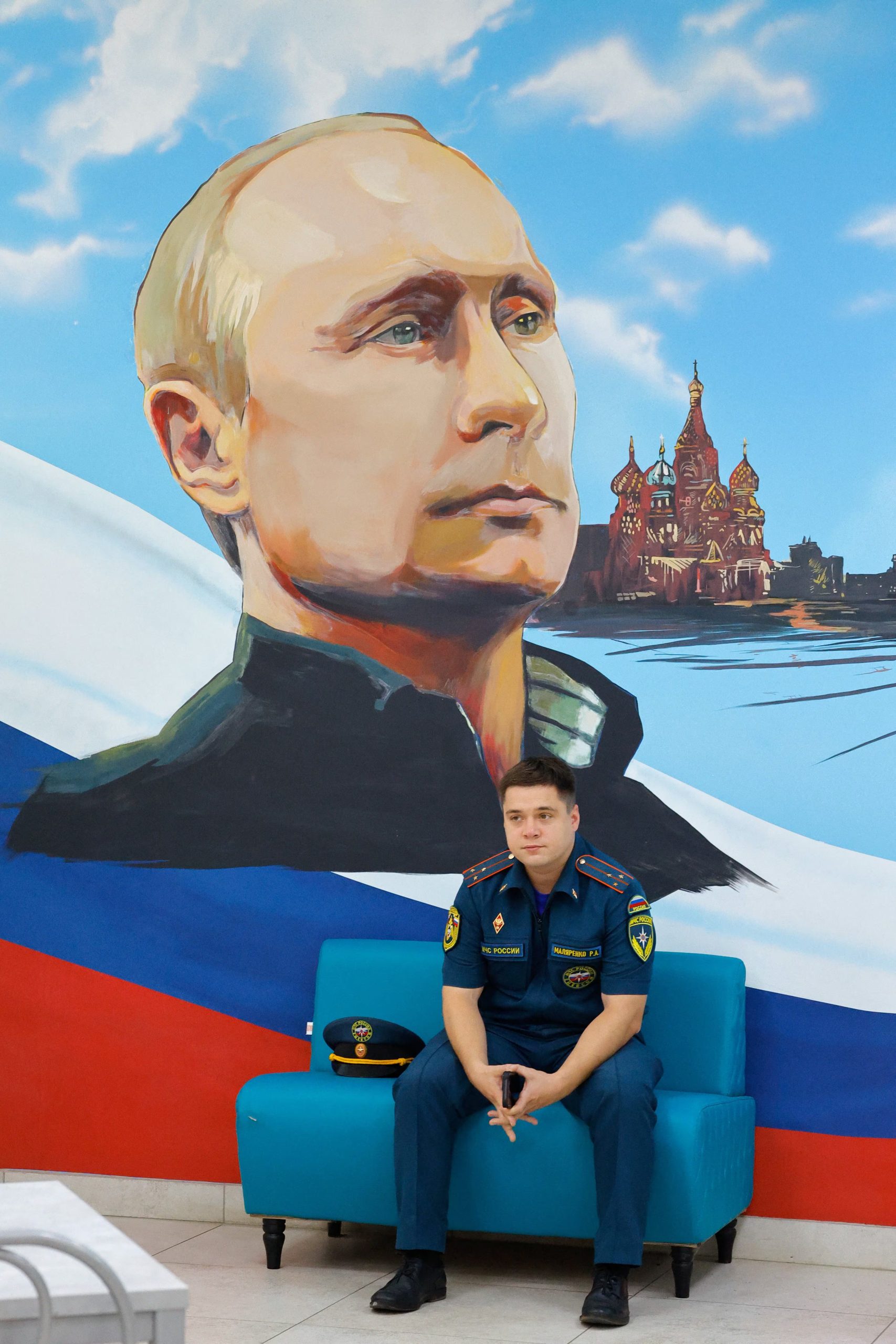 Un miembro del ministerio de Emergencias ruso, bajo un retrato de Putin, en un colegio de Donetsk, ciudad ucraniana bajo control ruso donde se votó por primera vez para la Duma. (REUTERS/Alexander Ermochenko)