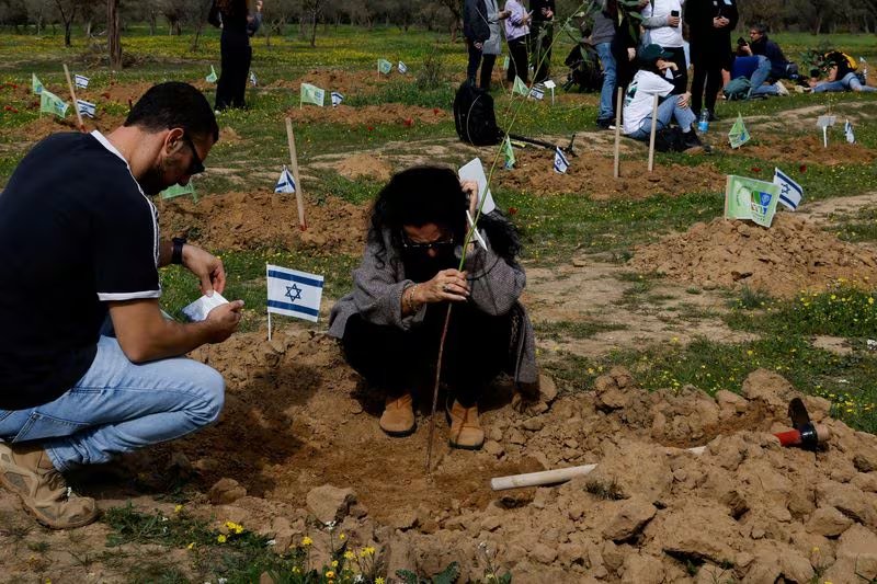 Familiares y cercanos plantan árboles en memoria de las personas que murieron y fueron secuestradas durante el ataque del 7 de octubre en la zona de la fiesta electrónica Nova (REUTERS/Tyrone Siu)