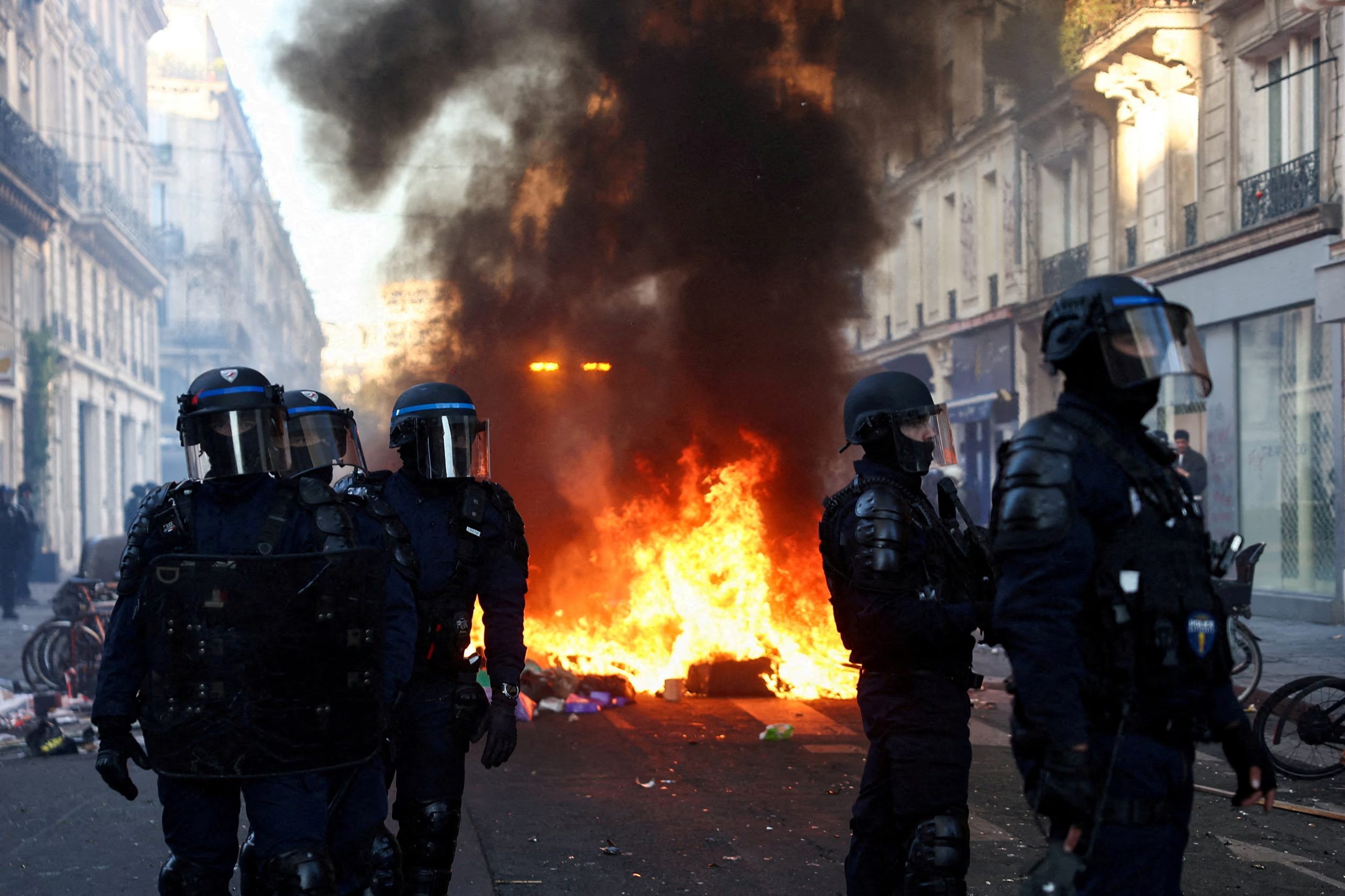 Un incendio arde mientras agentes de policía con equipo antidisturbios montan guardia durante disturbios civiles, al día siguiente de una jornada nacional de manifestaciones contra el costo de la vida y el aumento de los precios del combustible, en París, Francia, el 18 de octubre de 2026 (REUTERS/Abdul Saboor)