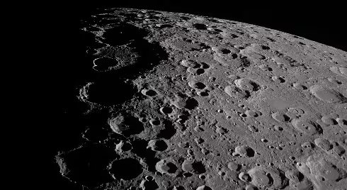 La observación de la Luna desde un arco de trayectoria distinto reveló detalles de montañas y cráteres contra el espacio.