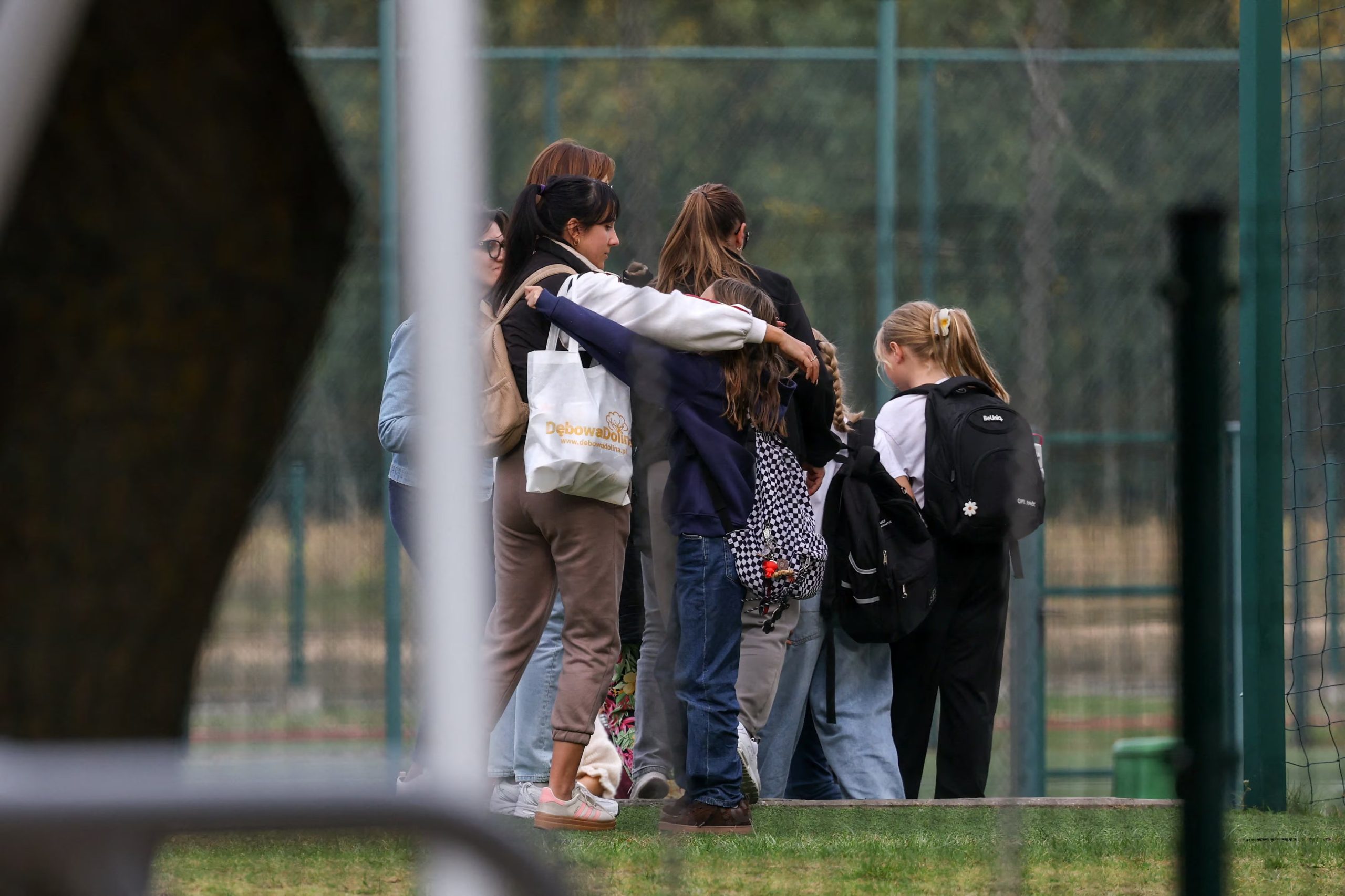 Una mujer abraza a un niño mientras los servicios de emergencia (no visibles en la imagen) trabajan en el lugar de un ataque mortal perpetrado en una escuela por un exalumno de 15 años, en Leszczydol-Nowiny (condado de Wyszków), al noreste de Varsovia, Polonia, el 8 de octubre de 2026 (REUTERS/Kacper Pempel)