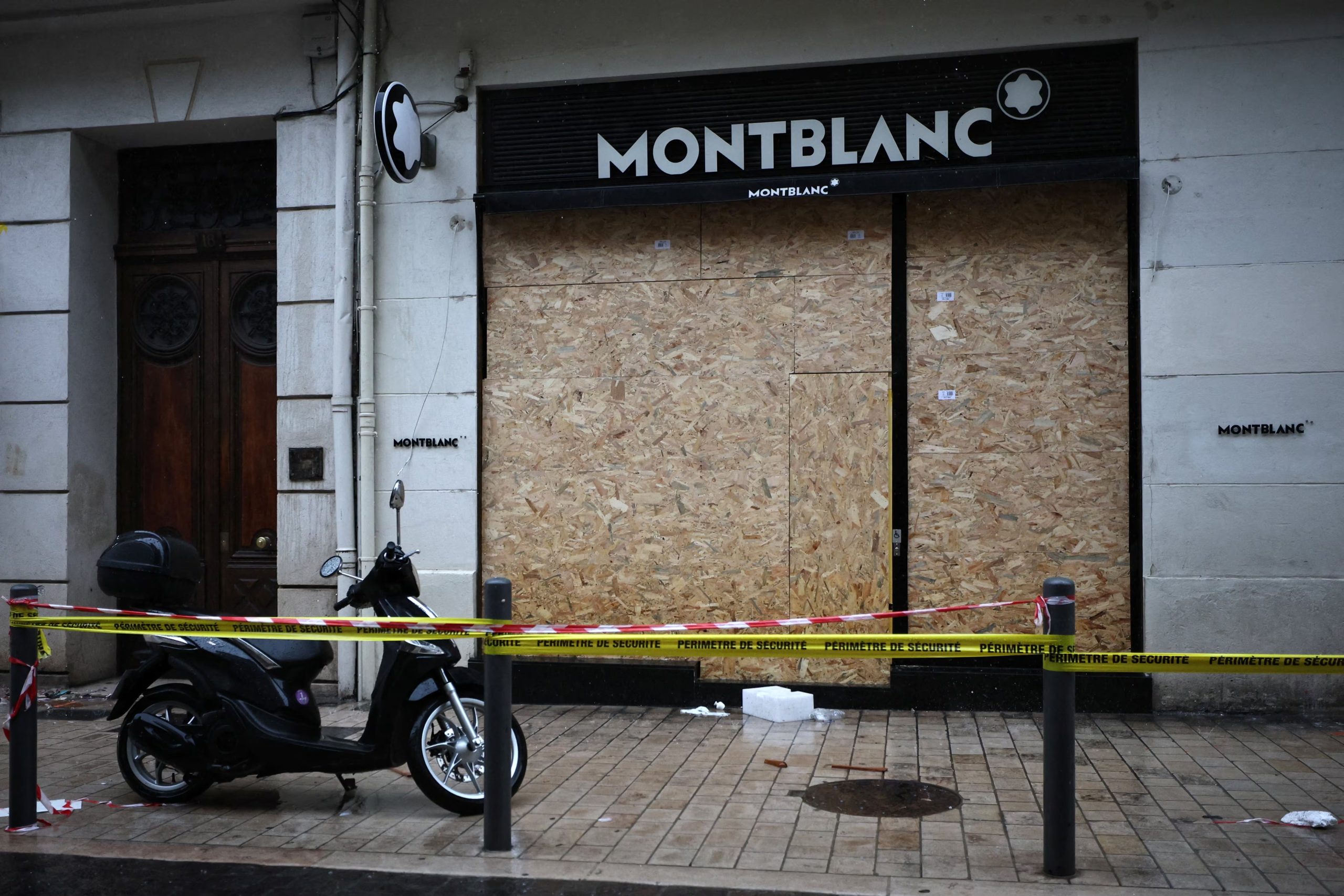 Una tienda Montblanc, objeto de actos vandálicos y con sus escaparates rotos cubiertos por paneles, se encuentra acordonada tras los enfrentamientos que estallaron durante una jornada nacional de manifestaciones contra el costo de la vida y el aumento de los precios del combustible, en Marsella, Francia, el 19 de octubre de 2026. REUTERS/Manon Cruz