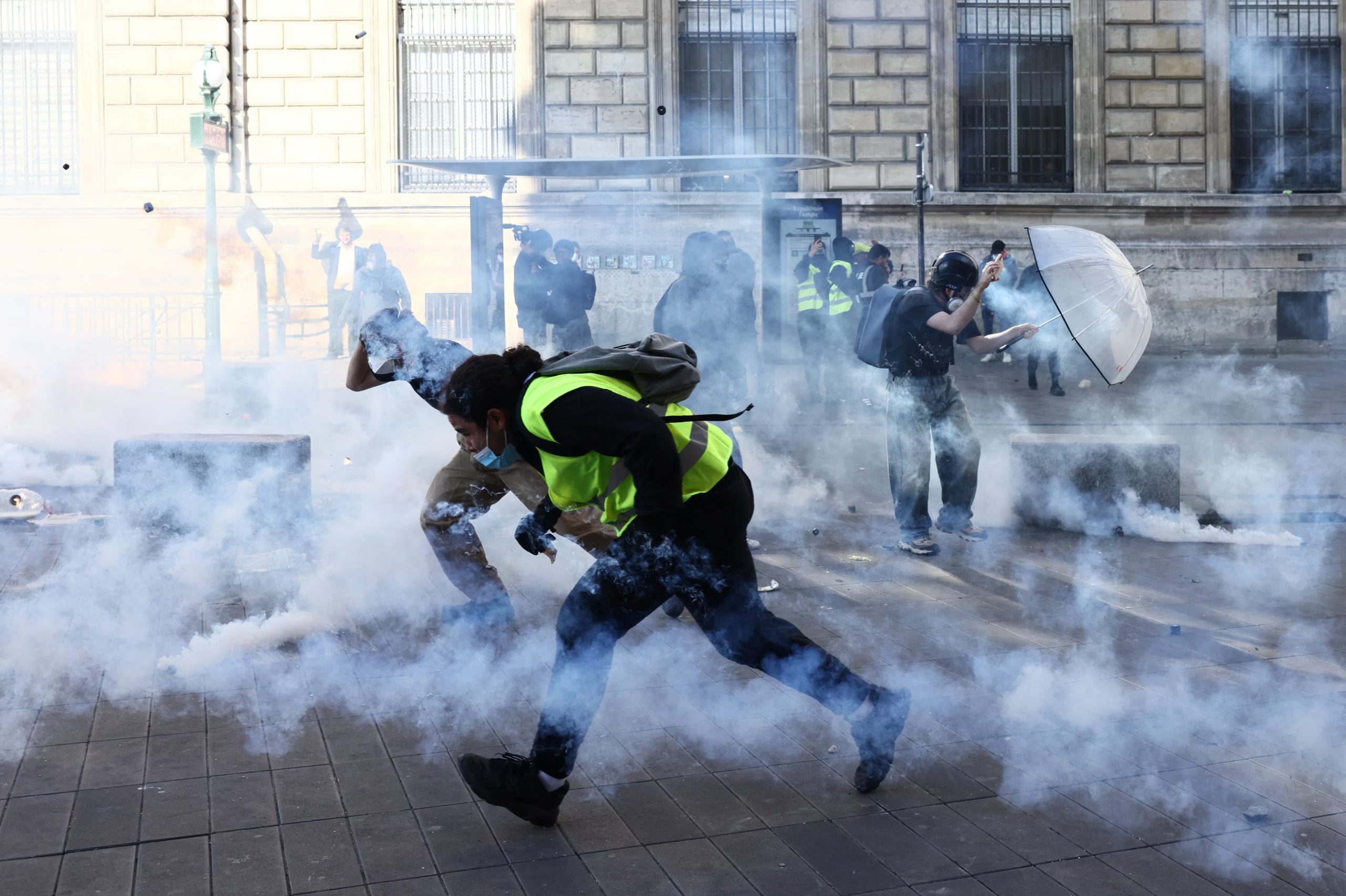 Manifestantes encapuchados corren entre gases lacrimógenos en medio de enfrentamientos con la policía francesa durante una manifestación contra el costo de vida y el aumento de los precios de los combustibles en la Plaza de la República de París (REUTERS/Jack Taylor)
