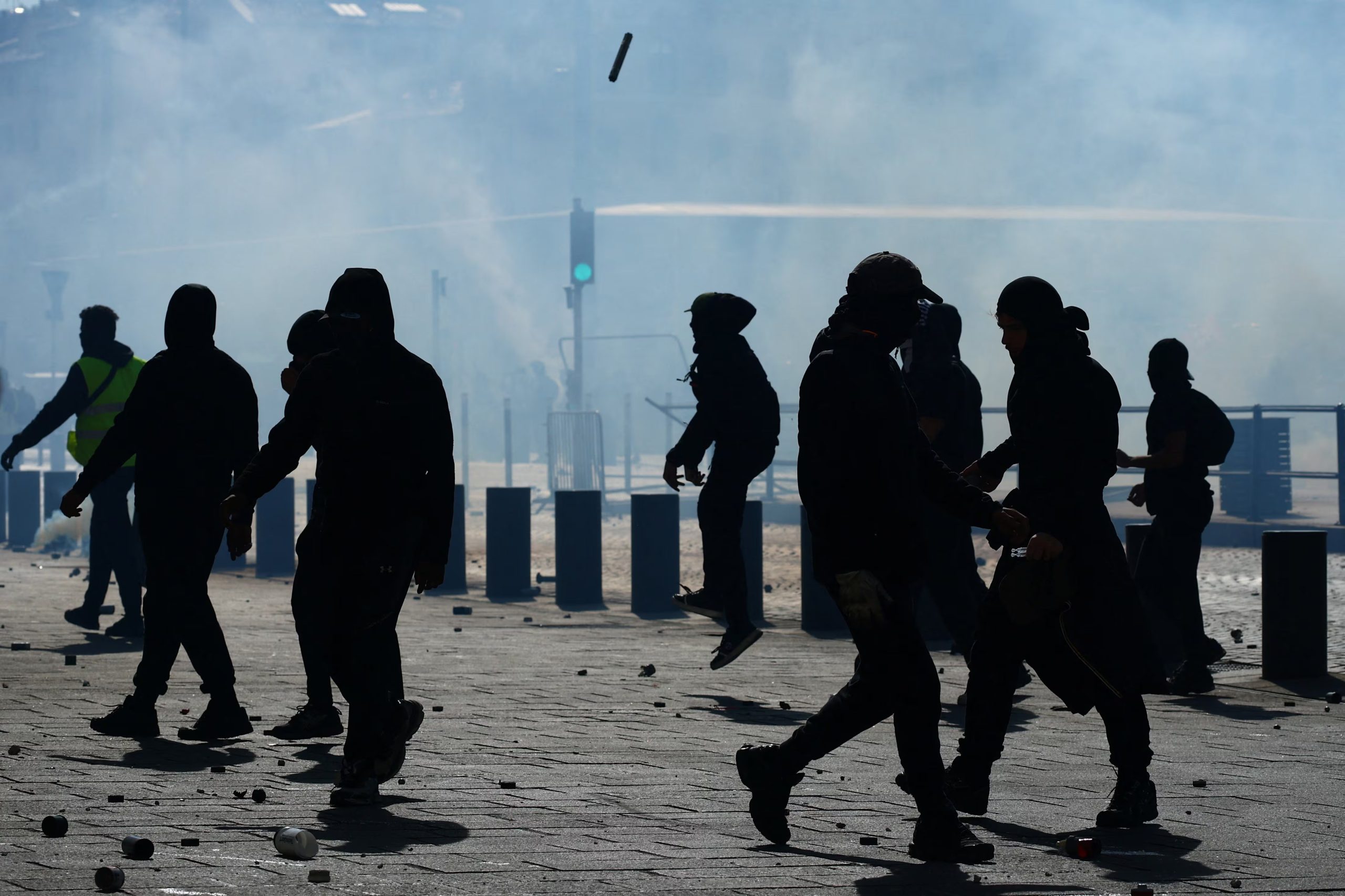 Manifestantes encapuchados caminan entre gases lacrimógenos (REUTERS/Manon Cruz)
