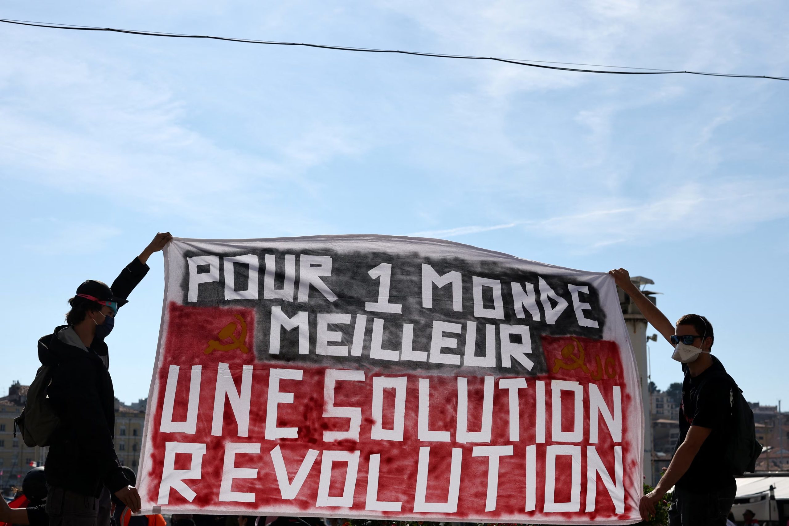 Manifestantes encapuchados sostienen una pancarta que dice: 