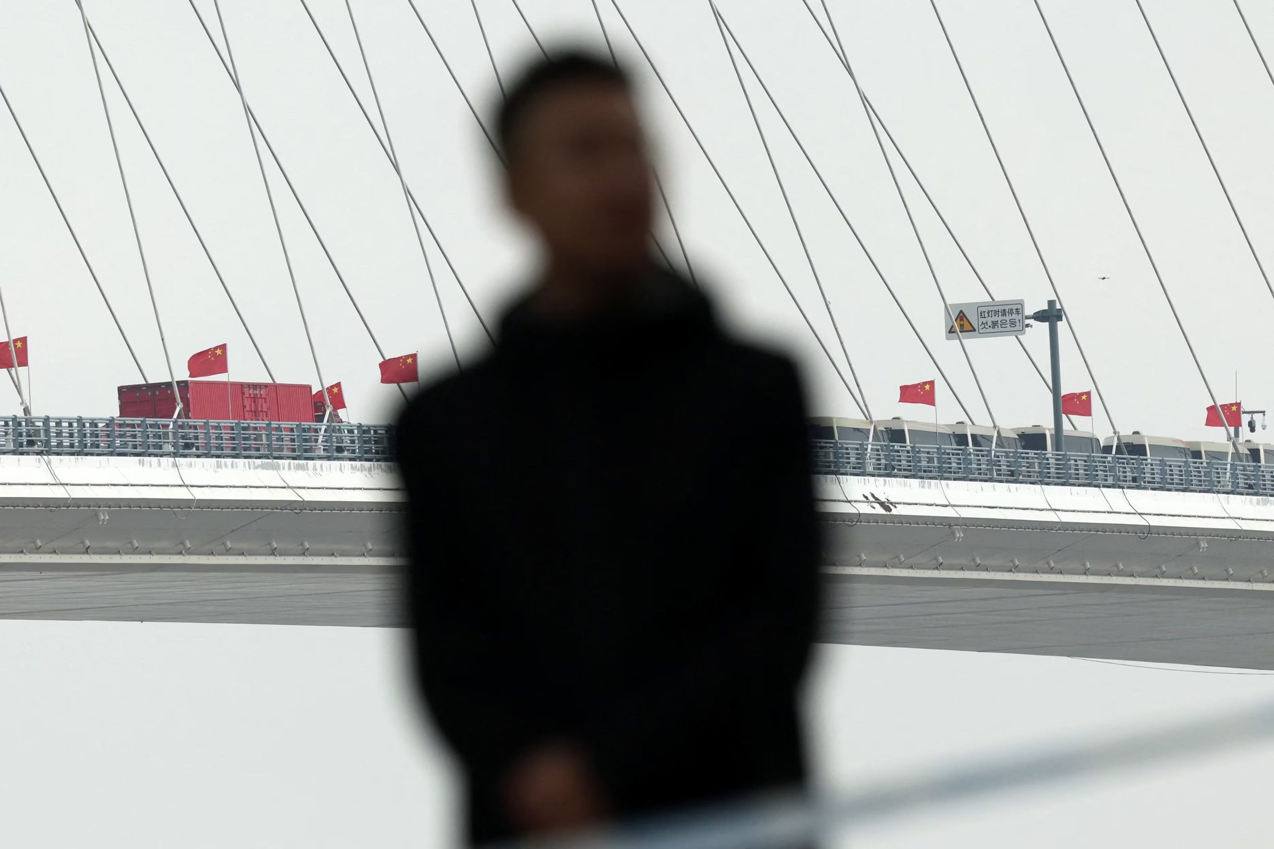 Un miembro del personal de seguridad vigila una zona ribereña acordonada durante la ceremonia de inauguración del Nuevo Puente del Río Yalu, el 15 de octubre de 2026 (REUTERS/Florence Lo)