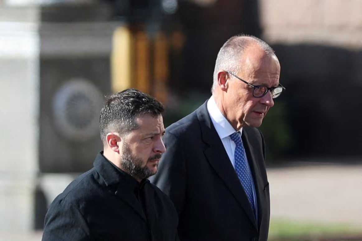 El presidente de Ucrania, Volodímir Zelenski, y el canciller alemán, Friedrich Merz, caminan mientras rinden homenaje en el monumento improvisado a los defensores ucranianos caídos, en medio del ataque de Rusia contra Ucrania, en la Plaza de la Independencia en Kiev, Ucrania, el 4 de octubre de 2026. REUTERS/Alina Smutko