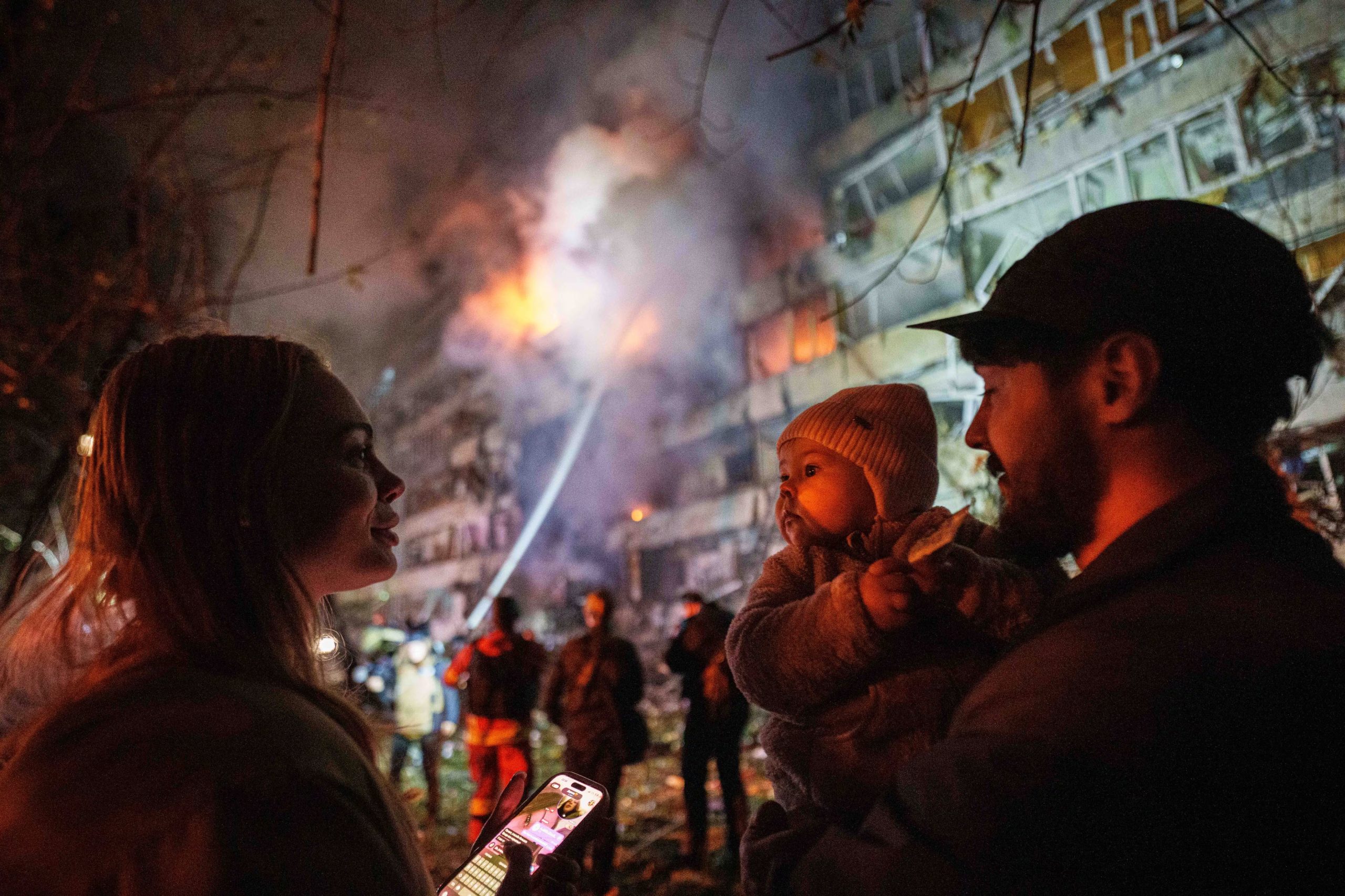 Victoria Deineko, su esposo, Ievhen Deineko y su hija, Mia, se ven junto a un edificio residencial de varias plantas dañado en Kiev, Ucrania, el martes 13 de octubre de 2026 (AP/Evgeniy Maloletka)